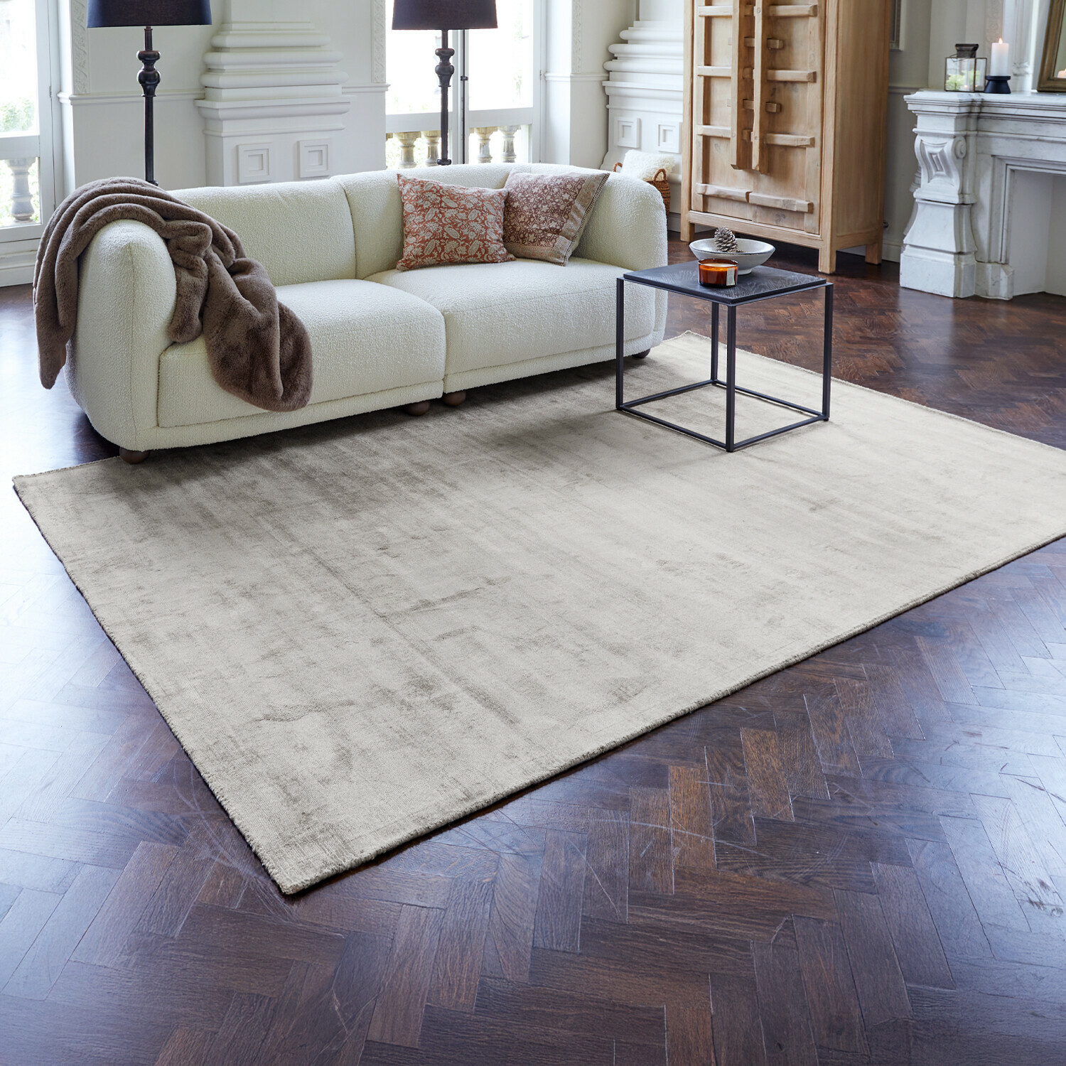 Heller beiger Teppich auf dunklem Holzboden im modernen Wohnzimmer mit weißem Sofa und schwarzem Tisch