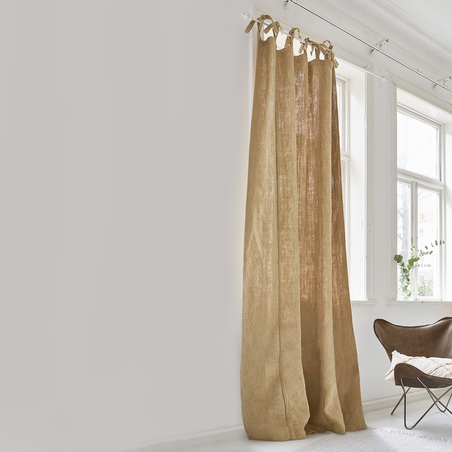 Gardine Uma Beiger Vorhang aus natürlichem Leinen in hellem Raum mit großem Fenster und braunem Sessel