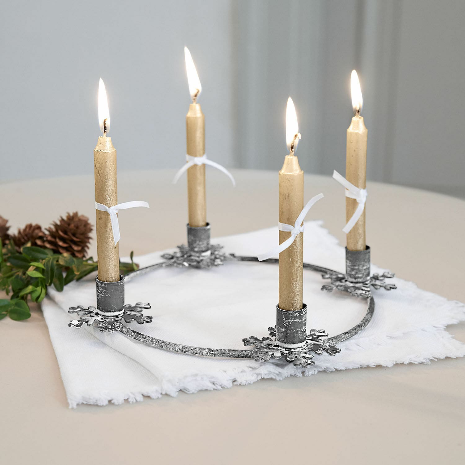 Kerzenständer Zarim Metall-Adventskranz mit vier goldfarbenen Kerzen auf weißem Stoff, festliche Weihnachtsdeko
