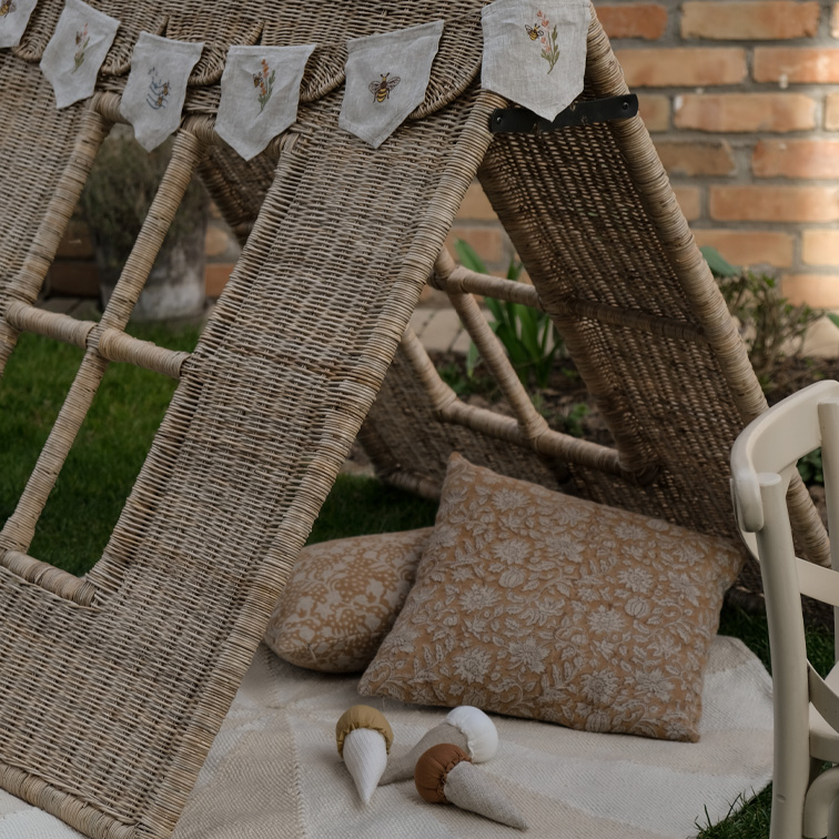 Wikliniges Zelt mit Kissen und bestickter Leinen-Girlande im Garten, natürliche Materialien und gemütliche Atmosphäre