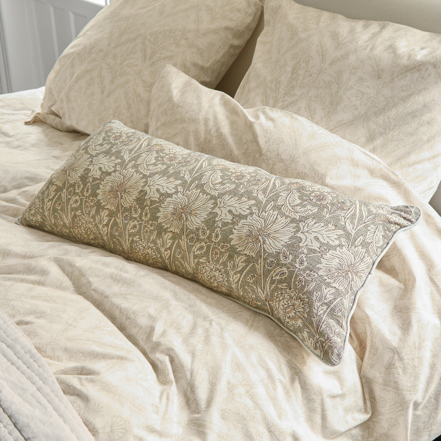 Beige Bettwäsche mit feinem Blumenmuster und dekorativem Kissen mit grüner Stickerei