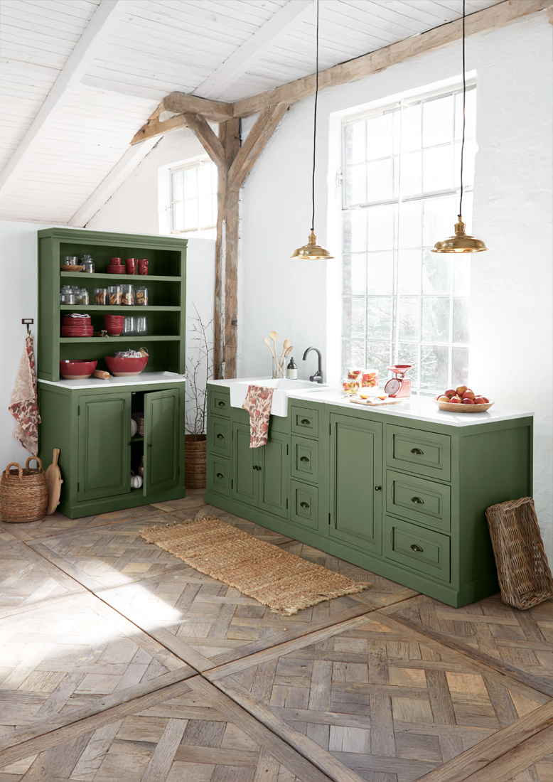 Grüne Holzküche mit weißer Arbeitsplatte und Messinglampen in hellem, rustikalem Raum
