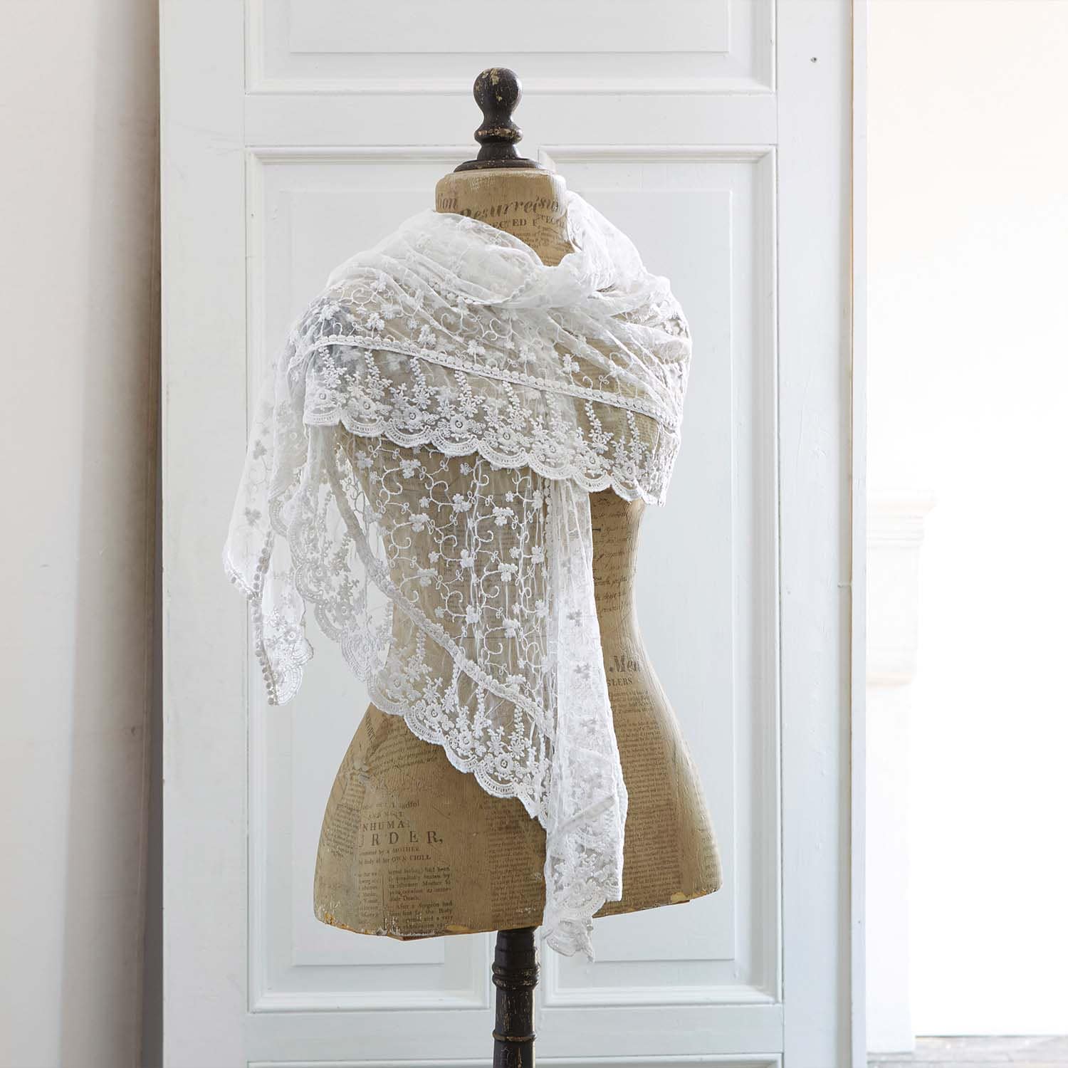 Feiner weißer Spitzen-Schal mit floralem Muster auf Schneiderpuppe, elegantes Modeaccessoire