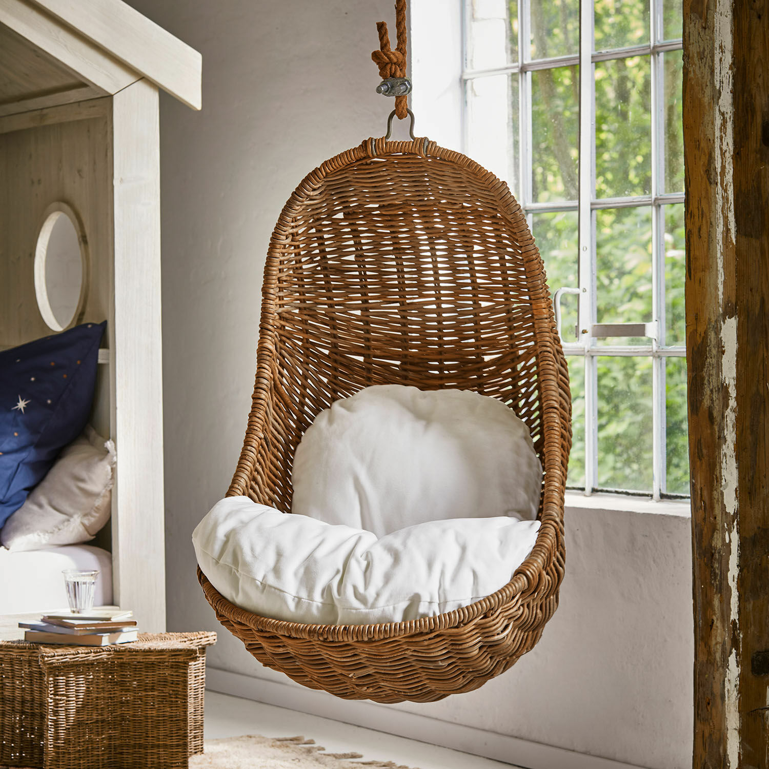 Kinderhängesessel Twinkla Hängesessel aus Rattan mit weißem Kissen in hellem, natürlichem Raum mit großem Fenster