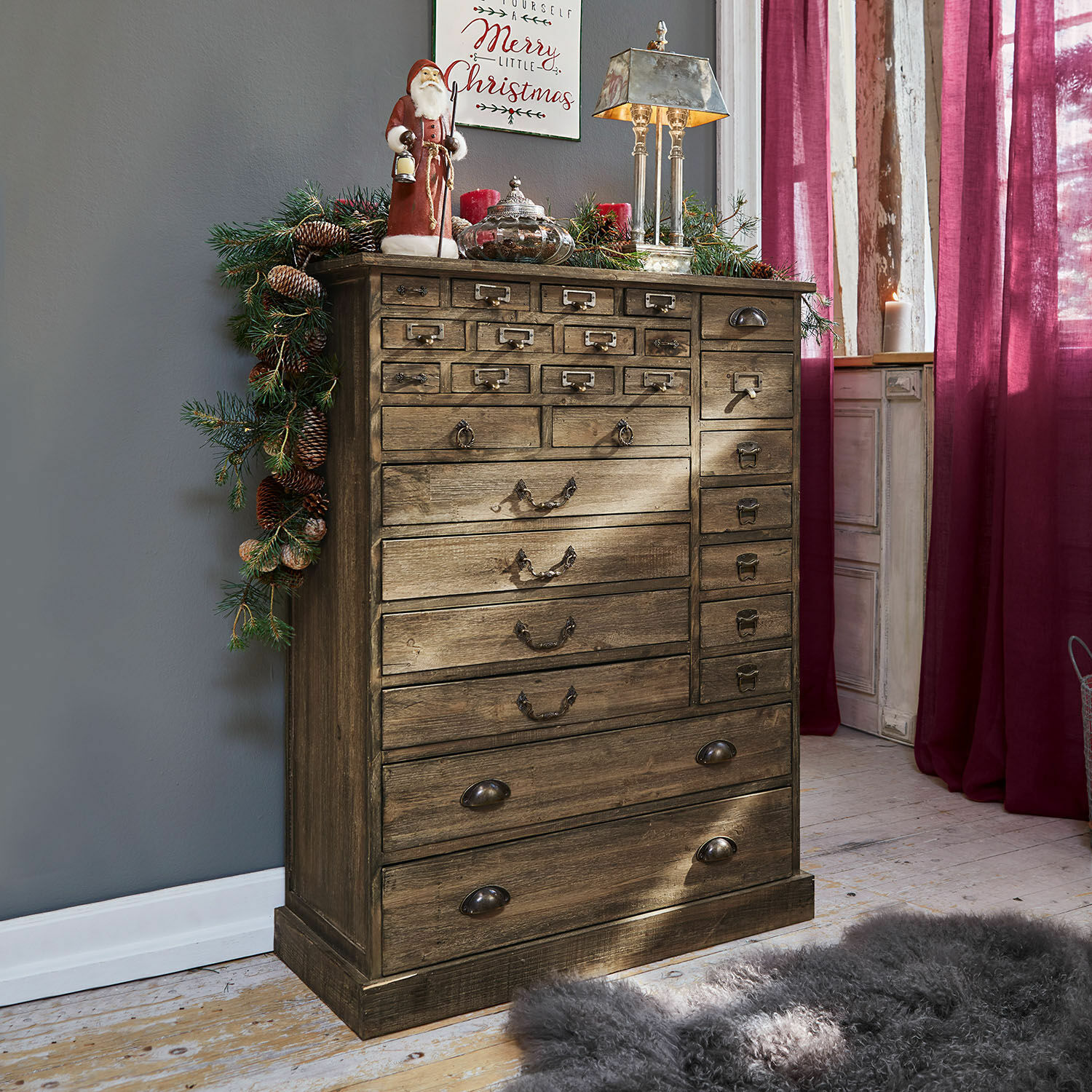 Vintage Holzkommode mit vielen Schubladen, weihnachtlich dekoriert mit Tannenzweigen und Lampe