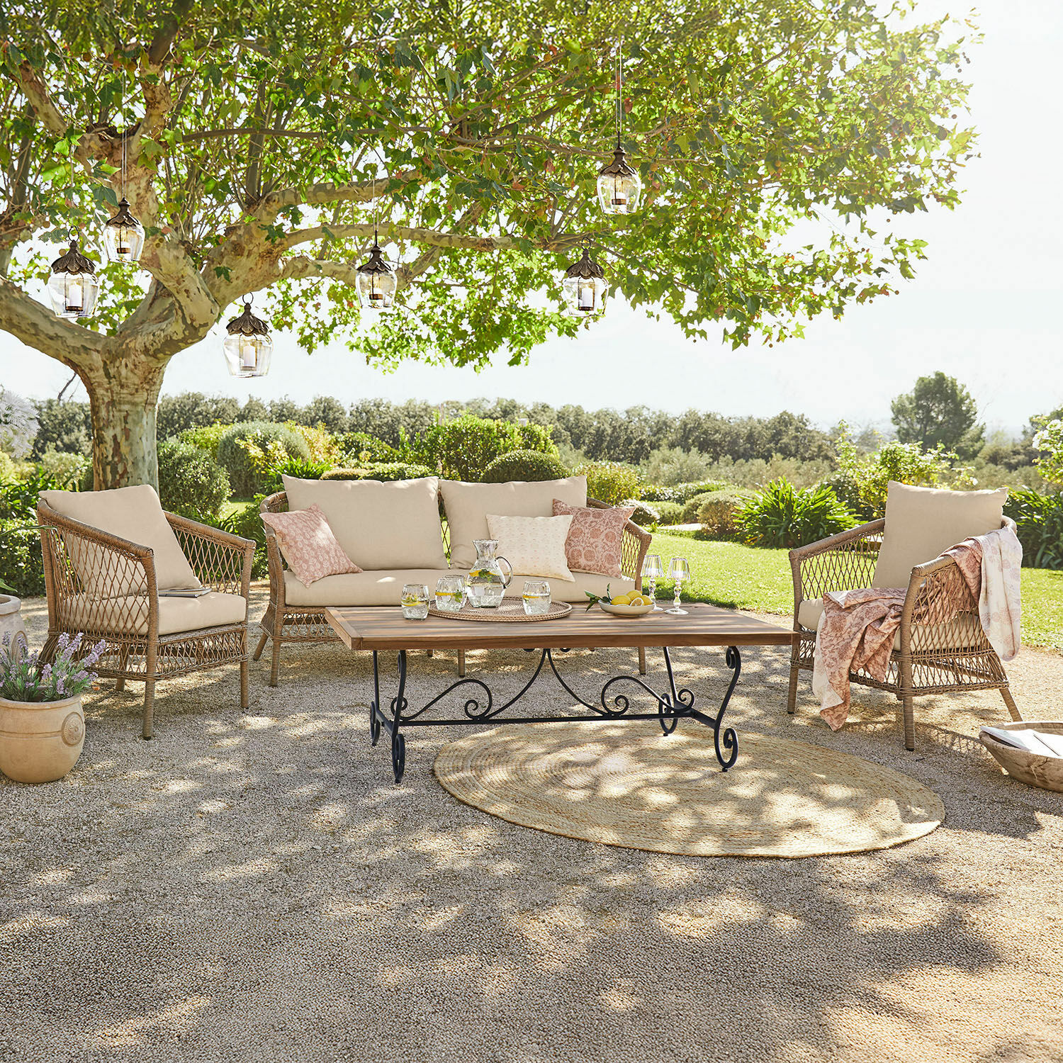 Sitzgruppe Farington Gartenmöbel-Set aus Rattan mit beigen Polstern und Holztisch auf Terrasse im grünen Garten