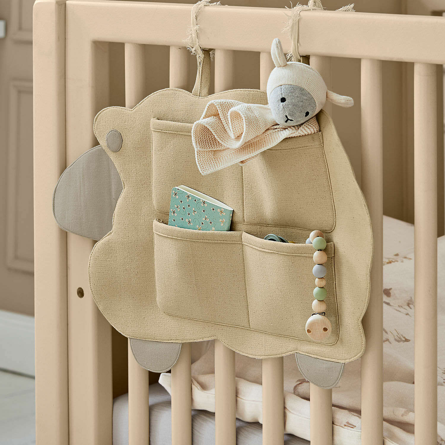 Wandorganizer Erianna Beiger Baumwoll-Organizer mit Taschen und Schaf-Plüsch an einem Kinderbett aus Holz