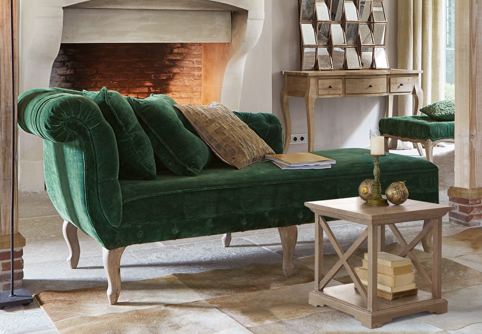 Klassisches grünes Samtsofa mit Holzbeinen in elegantem Wohnzimmer mit Kamin