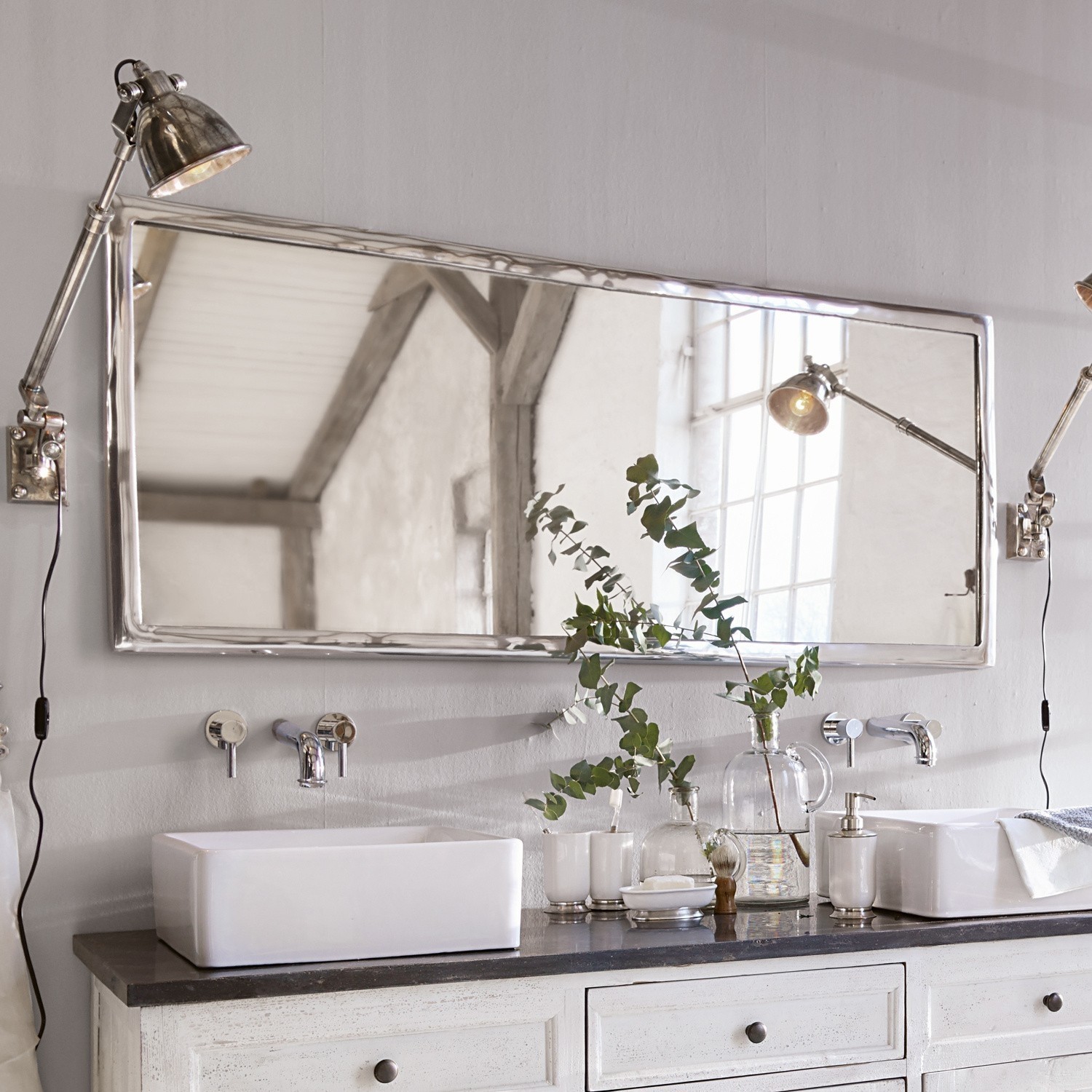 Großer rechteckiger Spiegel mit Metallrahmen über weißem Waschbecken auf schwarzer Arbeitsplatte im Bad