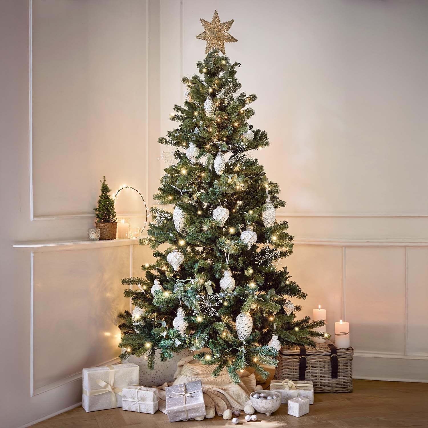 Weihnachtsbaum mit weißen Kugeln und Lichterkette geschmückt, Geschenke und Kerzen in gemütlichem Raum