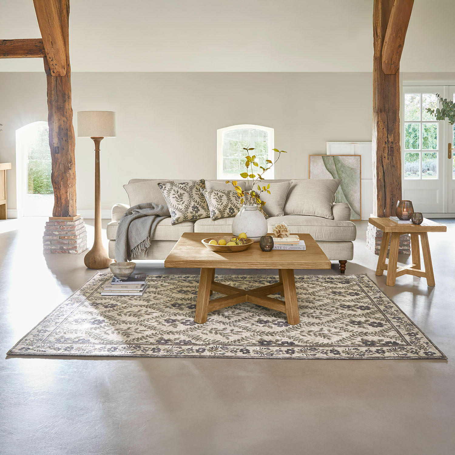 Gemütliches Wohnzimmer mit beigem Sofa, Holzcouchtisch und Teppich mit Pflanzenmuster