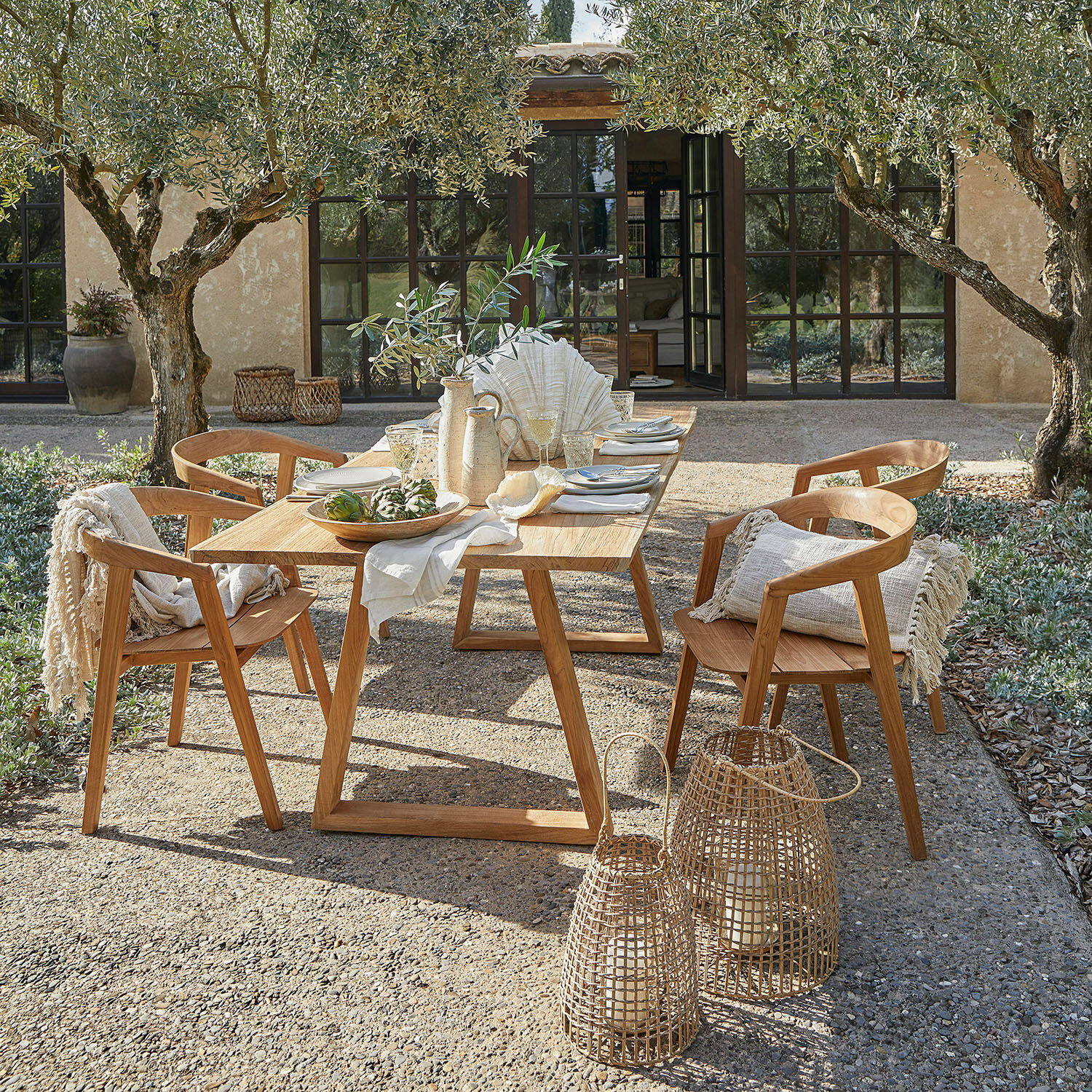 Tisch Saulny Gartenmöbel-Set aus natürlichem Teakholz mit Dekorationen und Laternen auf sonniger Terrasse