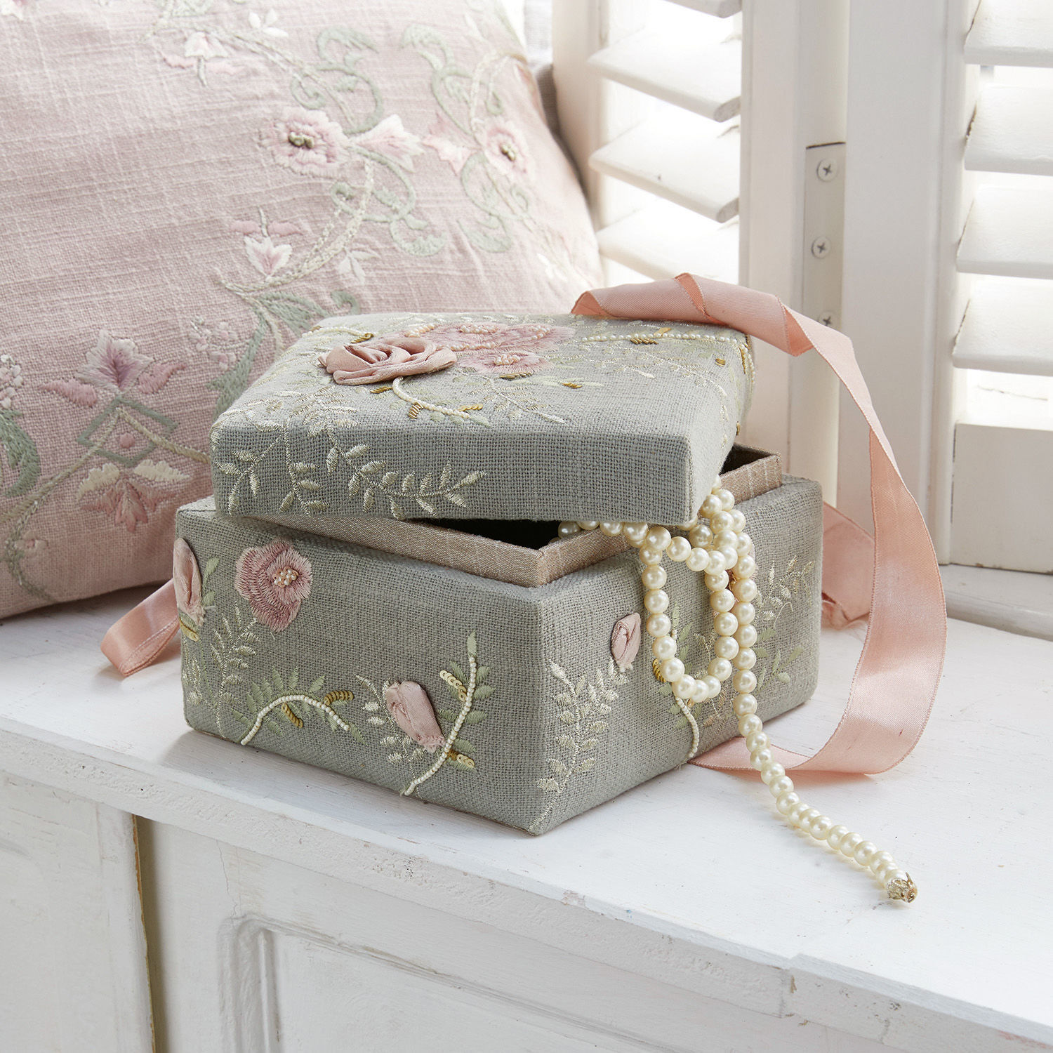 Graue Leinen-Schmuckbox mit Blumenstickerei und rosa Band, Perlenkette herausragend