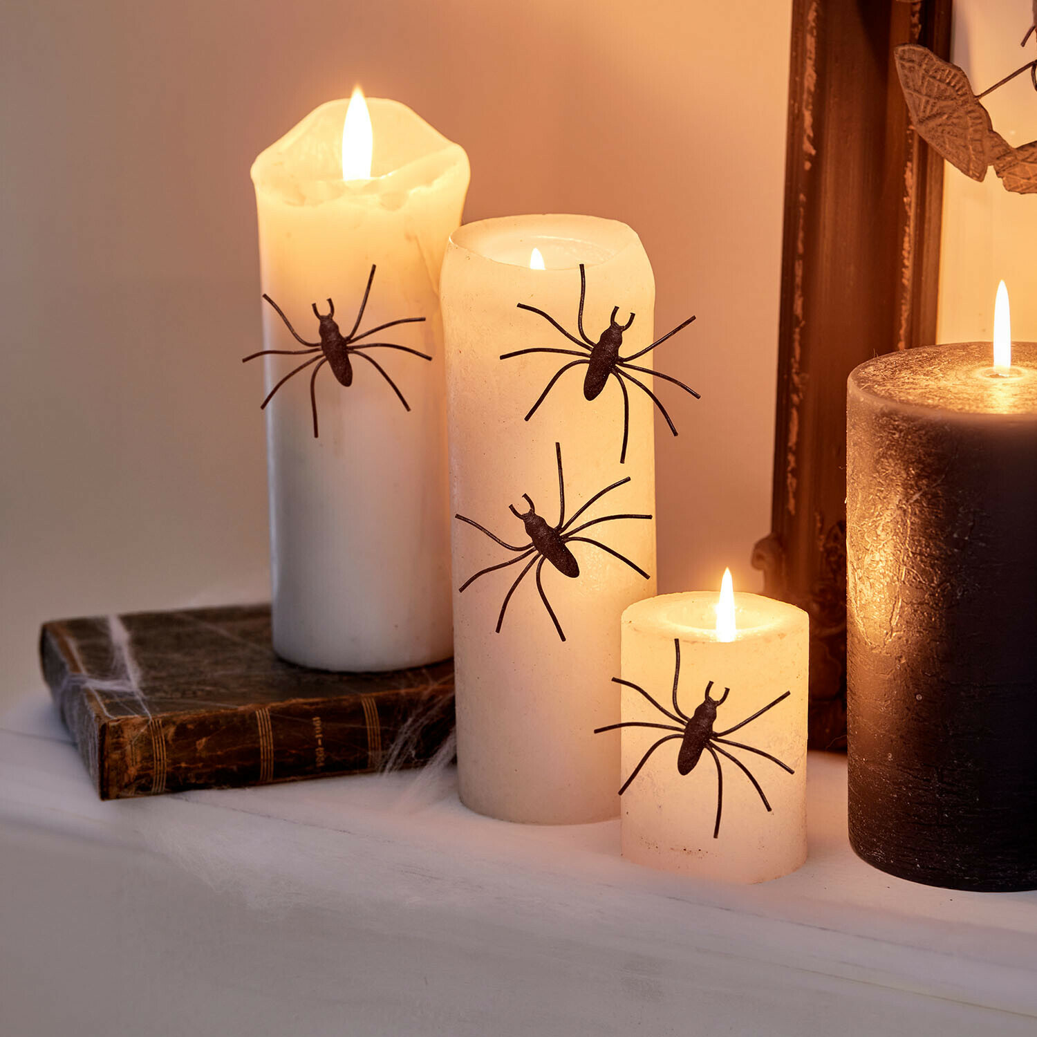 Weiße Dekokerzen mit schwarzen Spinnen für Halloween, stimmungsvolle Beleuchtung