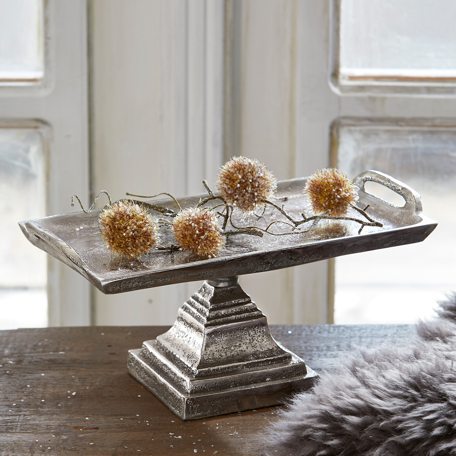 Silbernes Metalltablett auf Fuß mit dekorativen Kugeln auf Holztisch