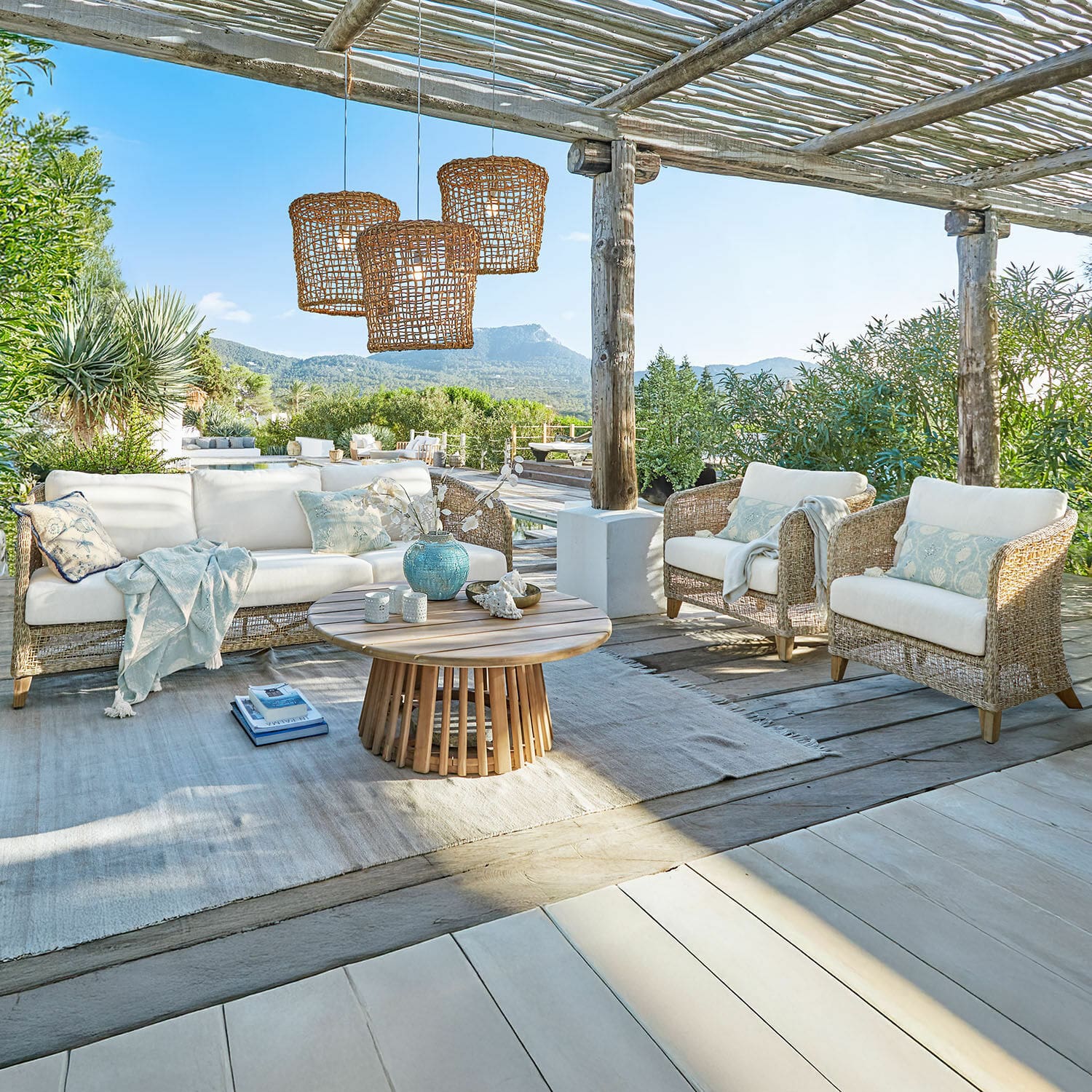 Sitzgruppe Clarivaux Gartenmöbel-Set aus natürlichem Rattan mit weißen Polstern und hellem Holztisch auf Terrasse
