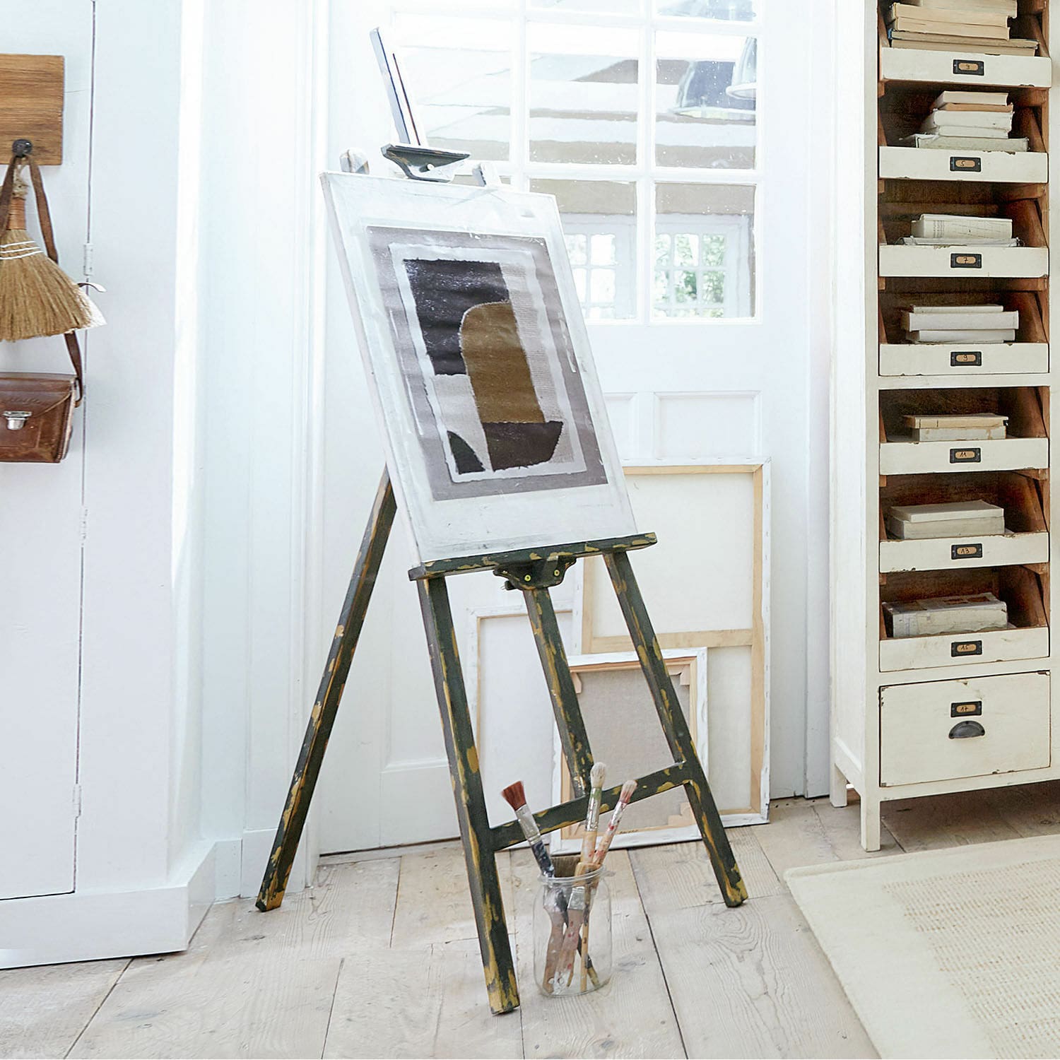 Staffelei Arabella Vintage Holz-Malstaffelei mit Bild und Pinseln auf hellem Holzboden in Atelier