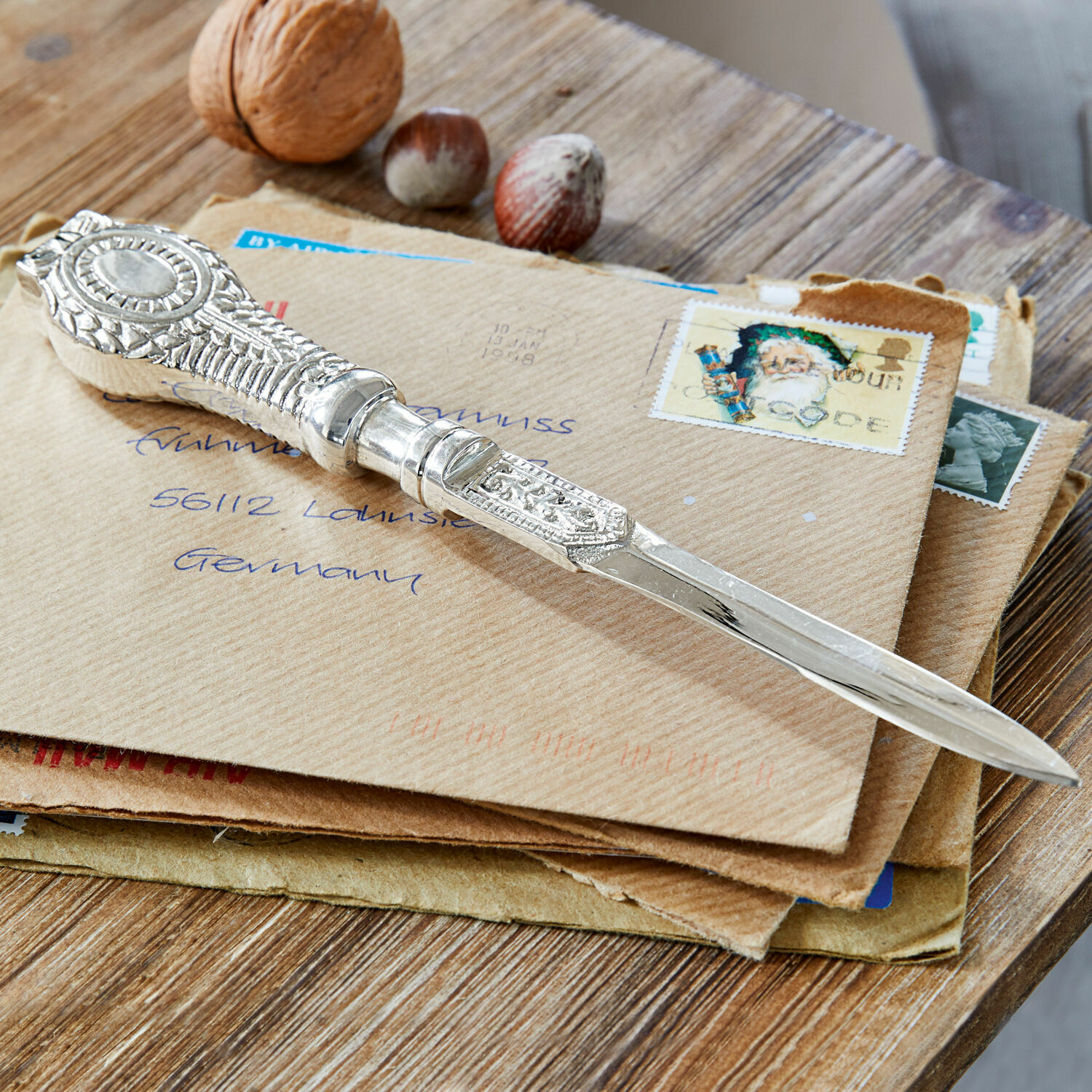 Brieföffner Parsifal Verziertes silbernes Briefmesser auf Briefumschlägen mit Nüssen auf Holztisch