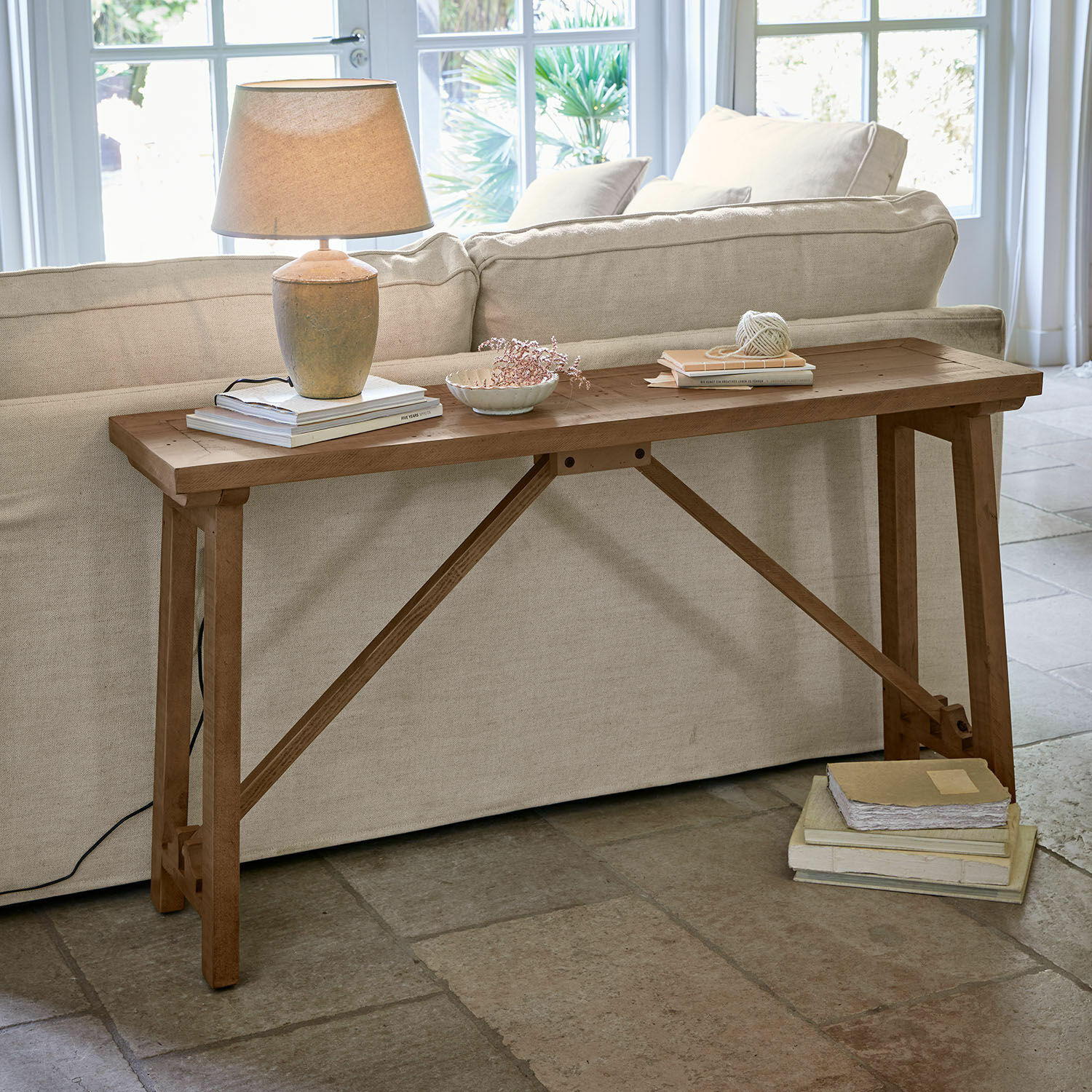 Konsole Flemming Holztisch in Naturfarbe hinter Sofa mit Lampe und Büchern, stilvolles Wohnzimmermöbel
