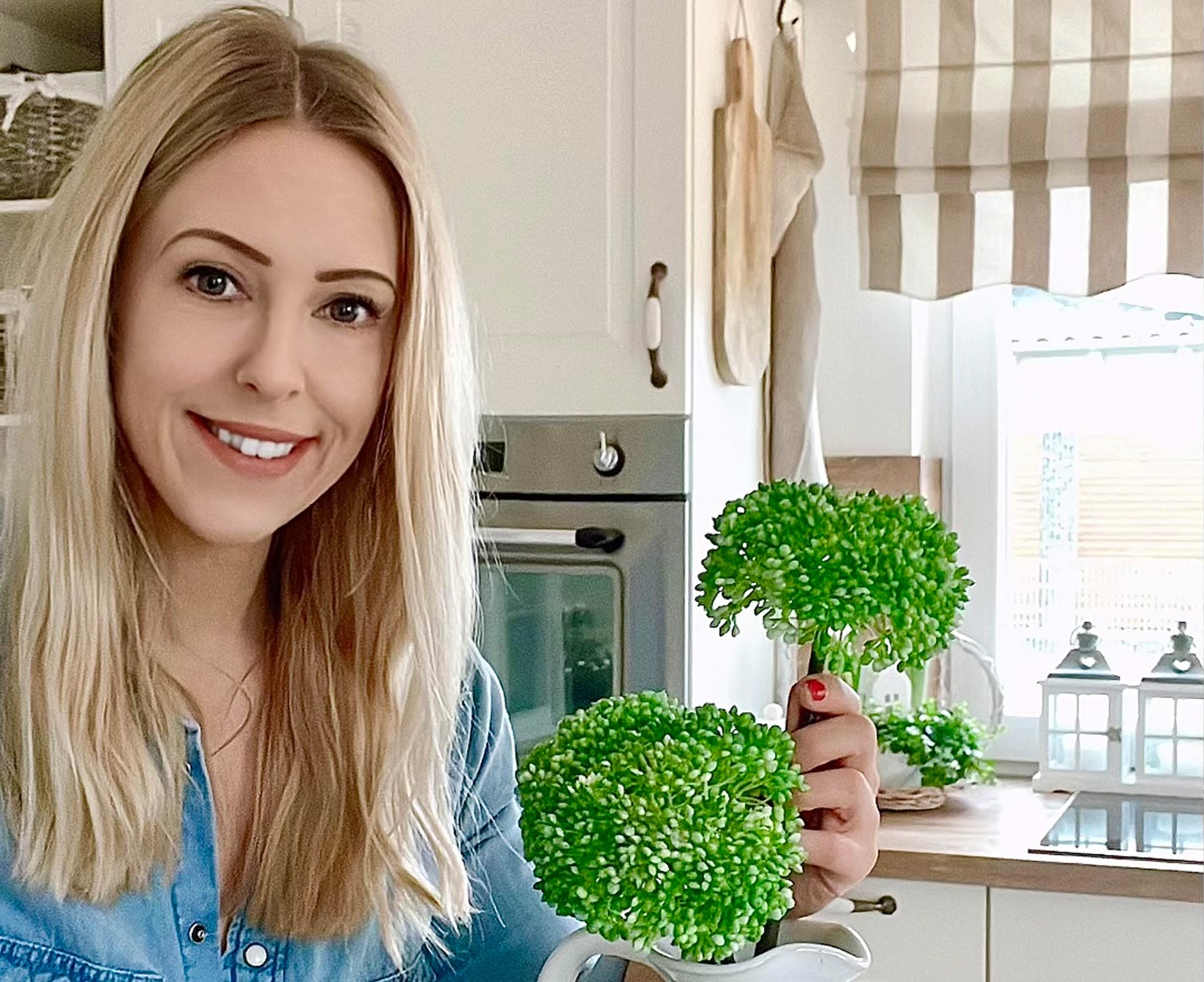 Frau in Küche hält grüne Dekoblumen in weißem Krug, rustikaler Landhausstil