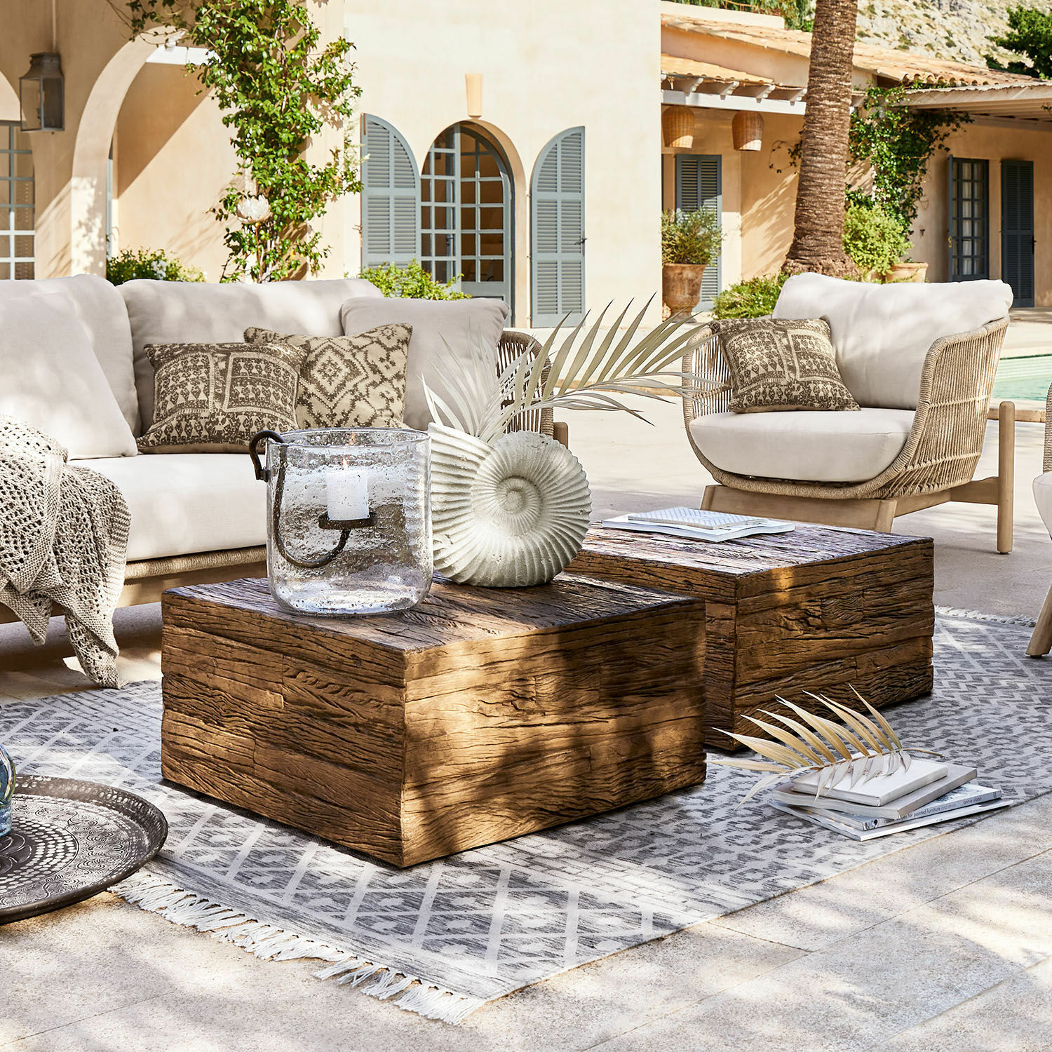 Couchtisch Glâne Gartenmöbel-Set mit hellen Polstern und Holztischen auf grauem Teppich auf der Terrasse