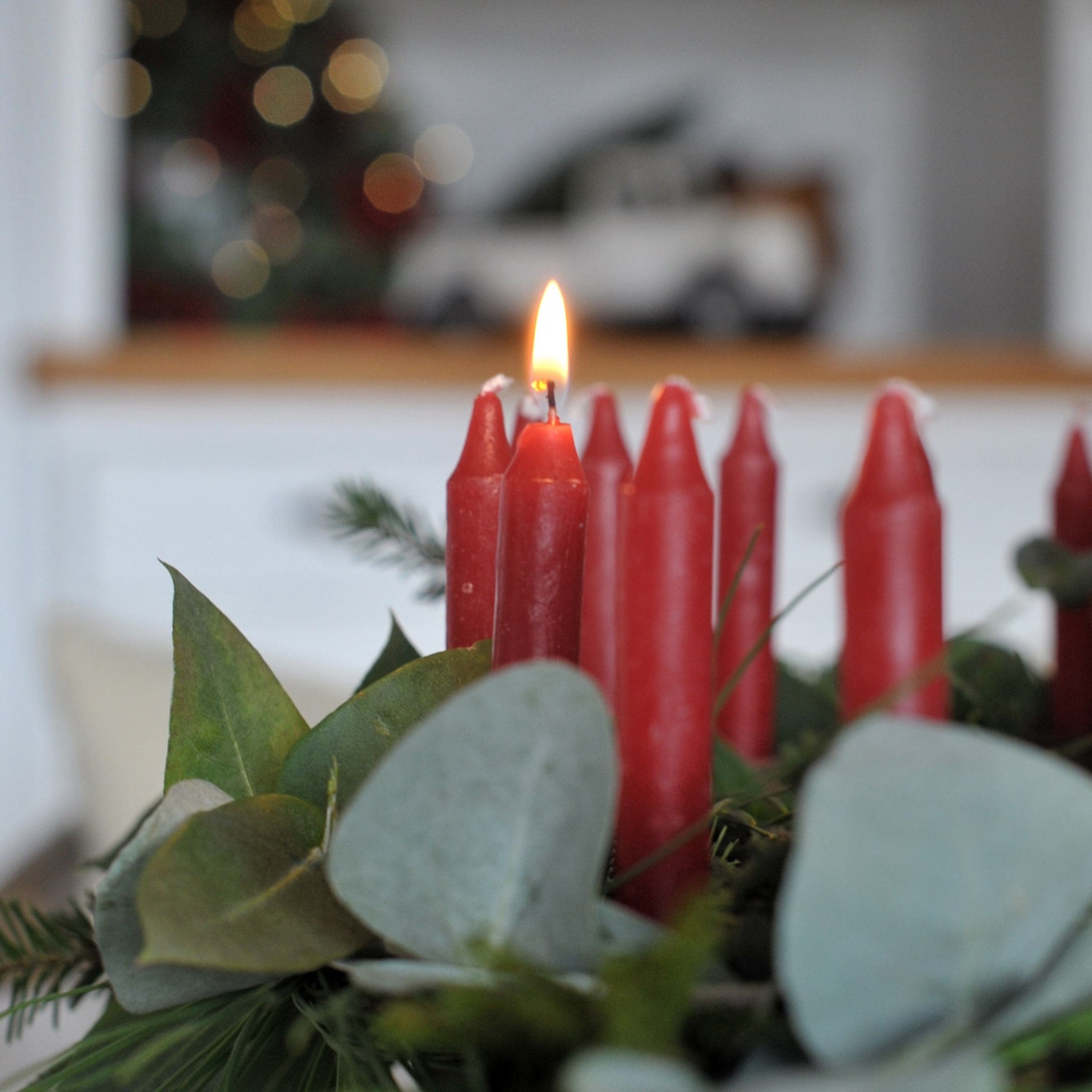 Rote Adventskerzen mit grünen Blättern als festliche Weihnachtsdekoration