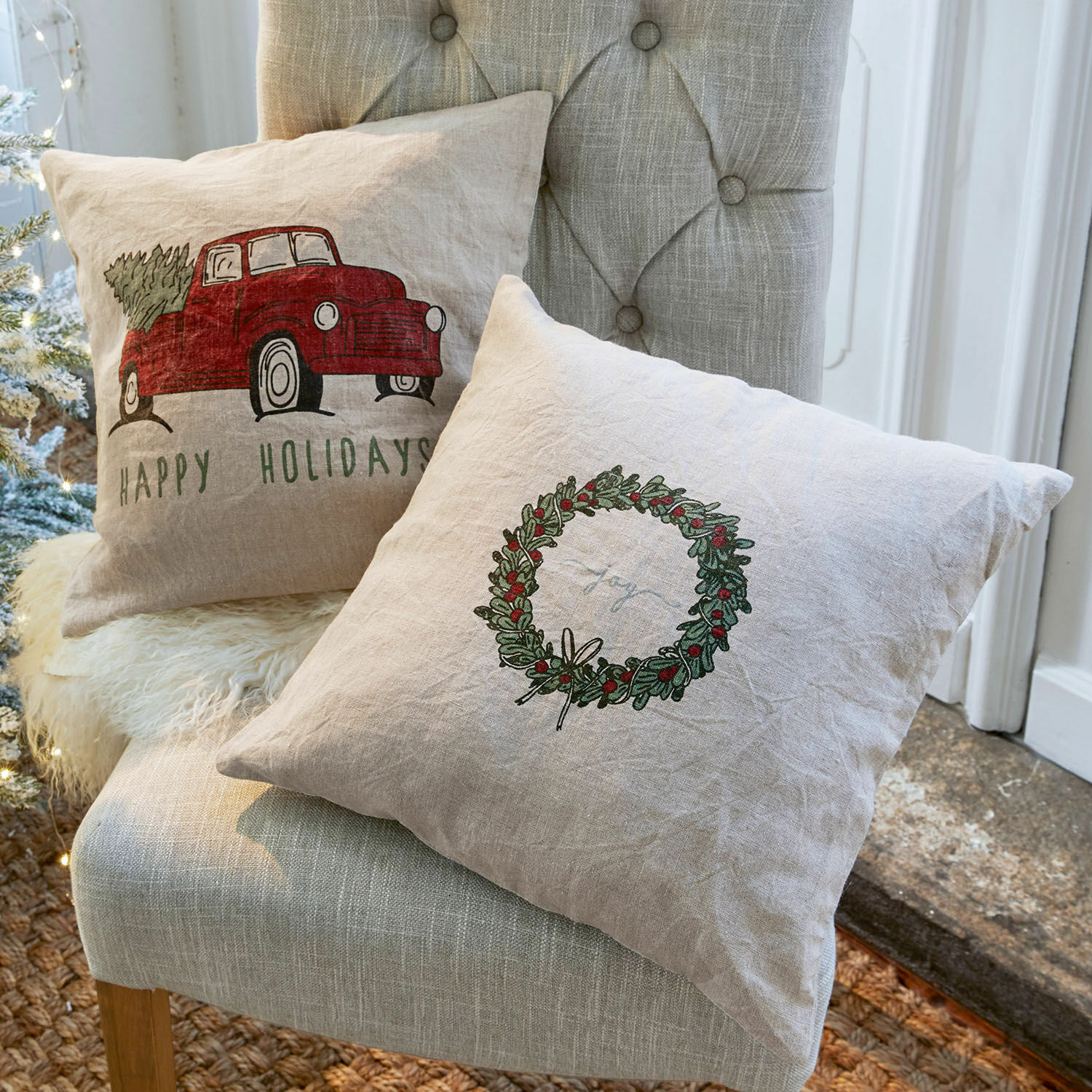 Kissenhülle 2er Set Camon Leinenkissen mit weihnachtlichen Motiven in Naturfarben auf grauem Stuhl dekorativ platziert