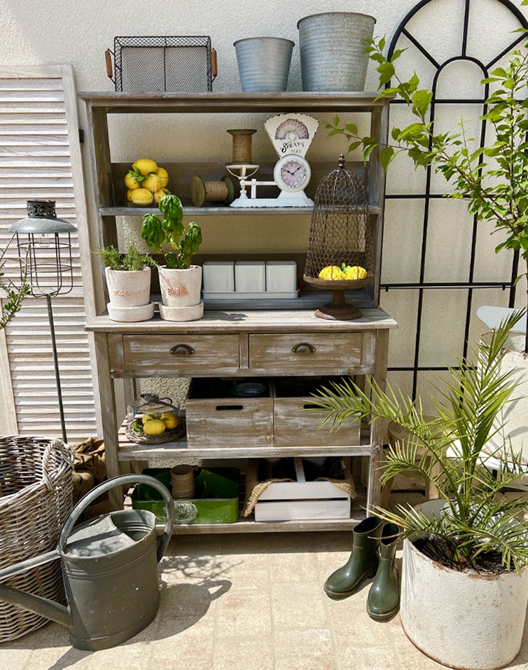Rustikaler Holzschrank mit Regalen und Schubladen im Vintage-Stil, Gartendekoration auf sonniger Terrasse