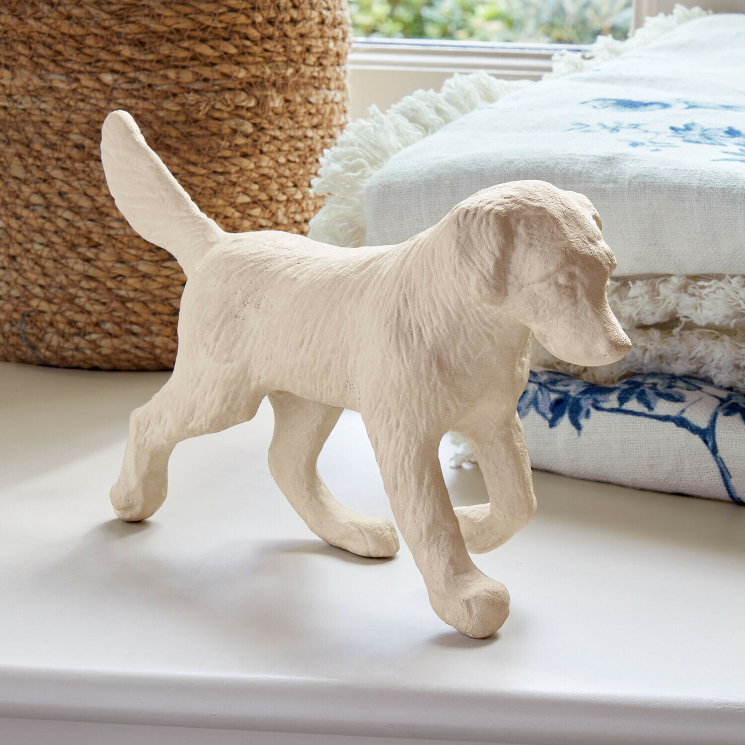Deko-Hund Wendrel Helle Hundefigur aus strukturiertem Material auf weißer Ablage mit dekorativem Stoff im Hintergrund