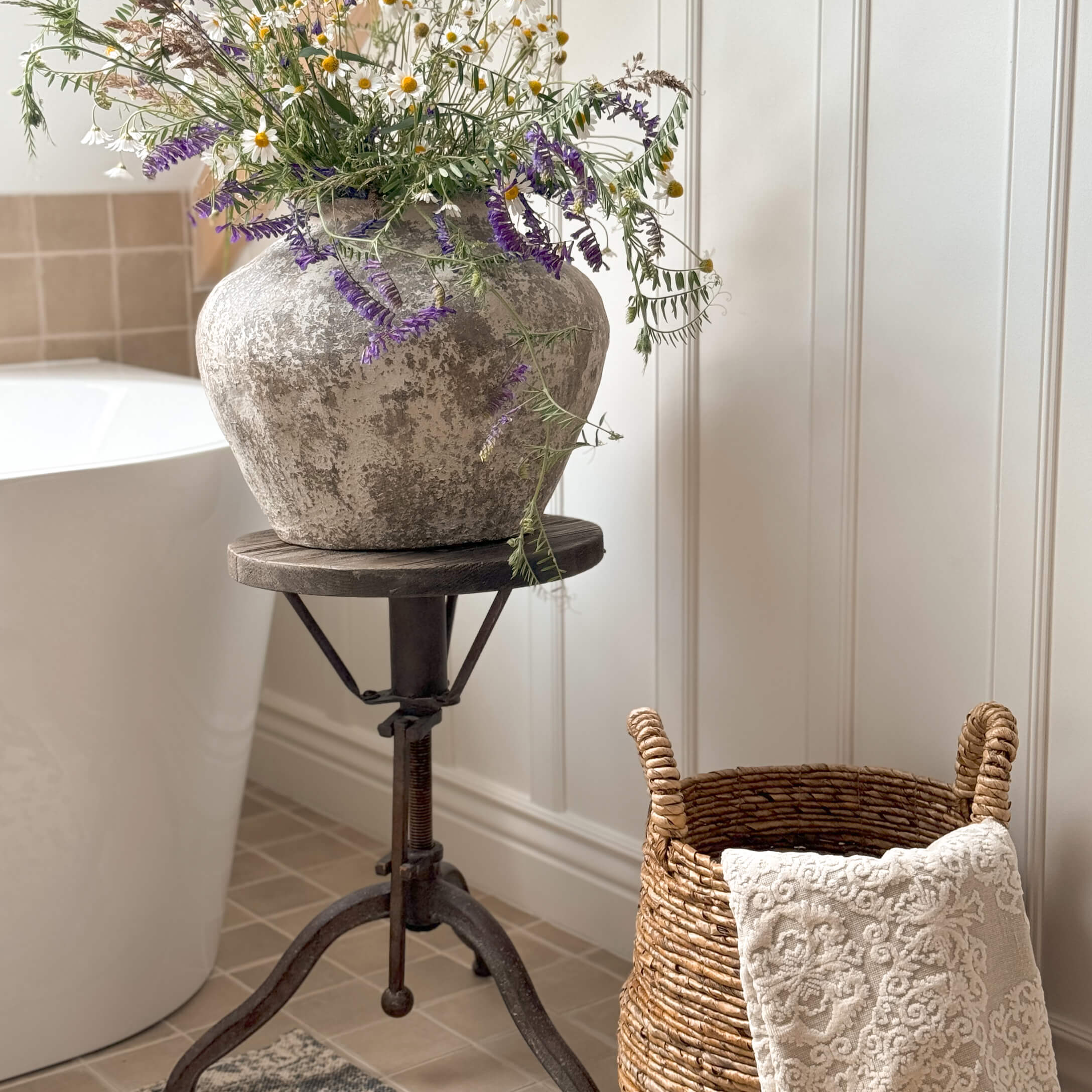 Rustikaler grauer Steinvase mit Wildblumen auf einem Metallständer im Badezimmer