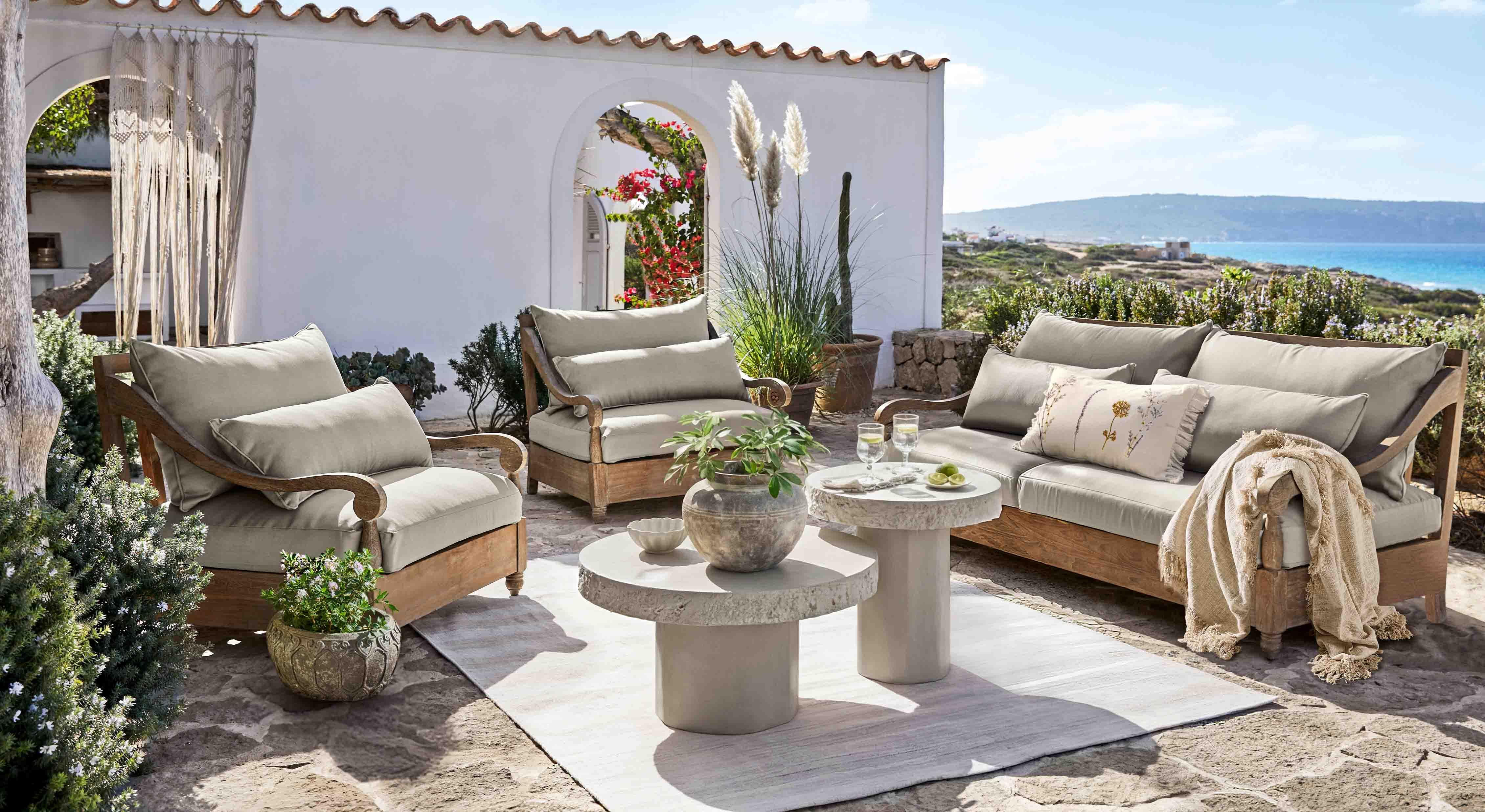 Gartenmöbel-Set aus Holz mit grauen Polstern auf Terrasse mit Meerblick