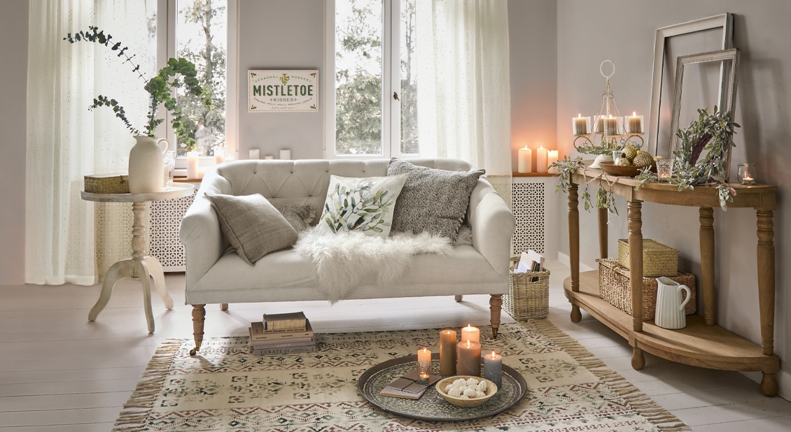 Gemütliches Wohnzimmer mit beigem Sofa, Holztisch und Kerzen auf Teppich, Winterdekoration