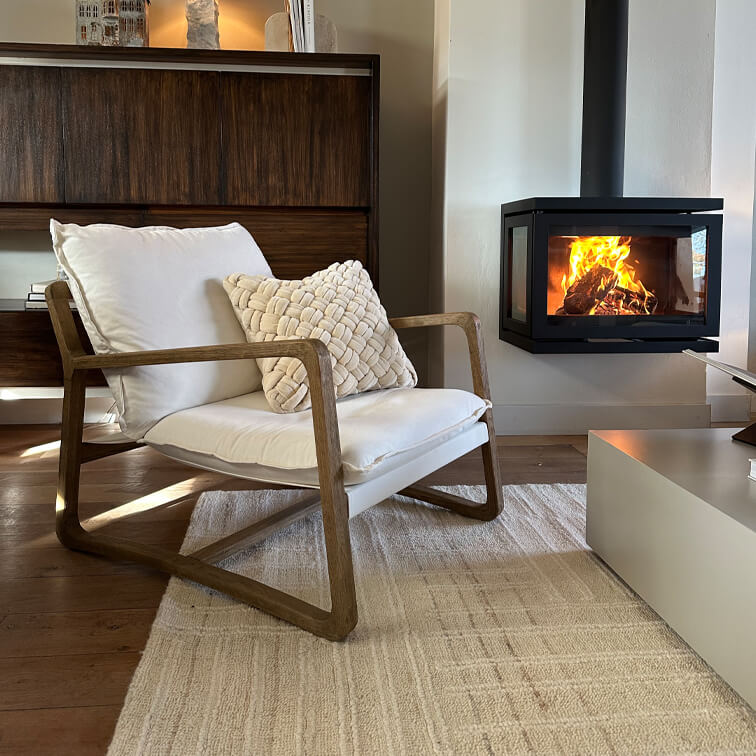 Holzstuhl mit weißem Polster neben modernem Kamin in gemütlichem Wohnzimmer