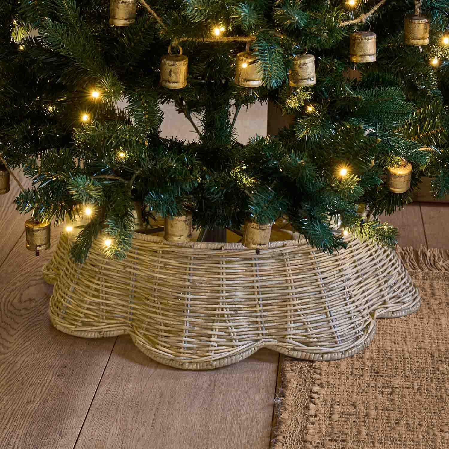 Natürlicher hellbrauner Korbständer aus Weide unter einem grünen Weihnachtsbaum mit warmen Lichtern
