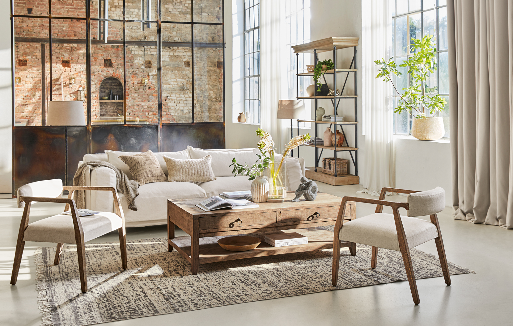 Gemütliches Loft-Wohnzimmer mit Holztisch, cremefarbener Couch und zwei Stühlen auf Teppich
