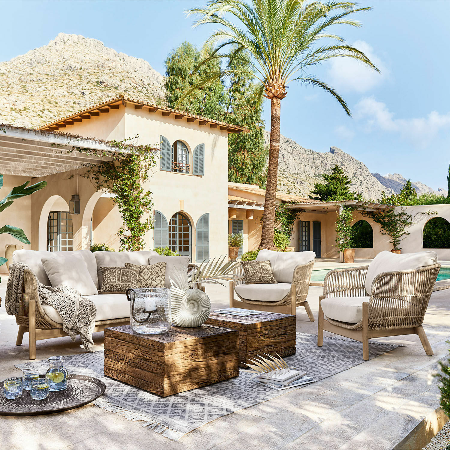 Sitzgruppe FSC®-100% Belvidere Outdoor-Möbelset mit beigen Polstern und Holztisch auf Terrasse neben Pool in mediterranem Stil