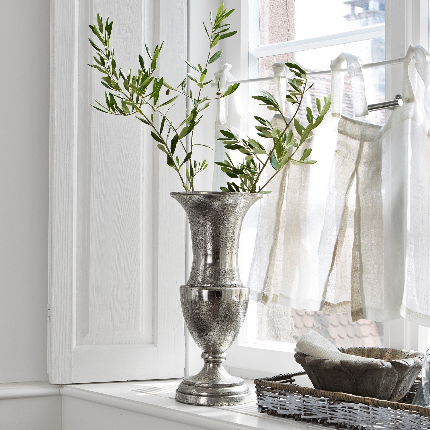 Vase Gilberta Silberne Metallvase auf Fensterbank mit grünen Zweigen und natürlichem Licht
