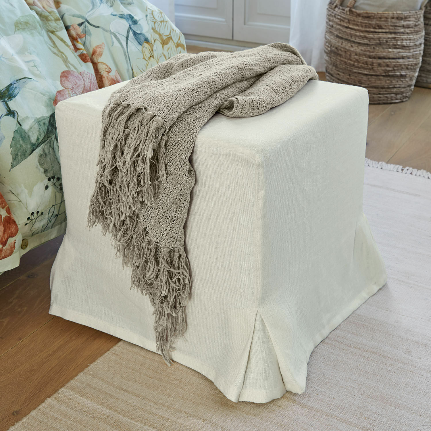 Hocker Ulysette Beiger Stoffhocker mit grauer Strickdecke auf Holzboden in gemütlichem Wohnraum