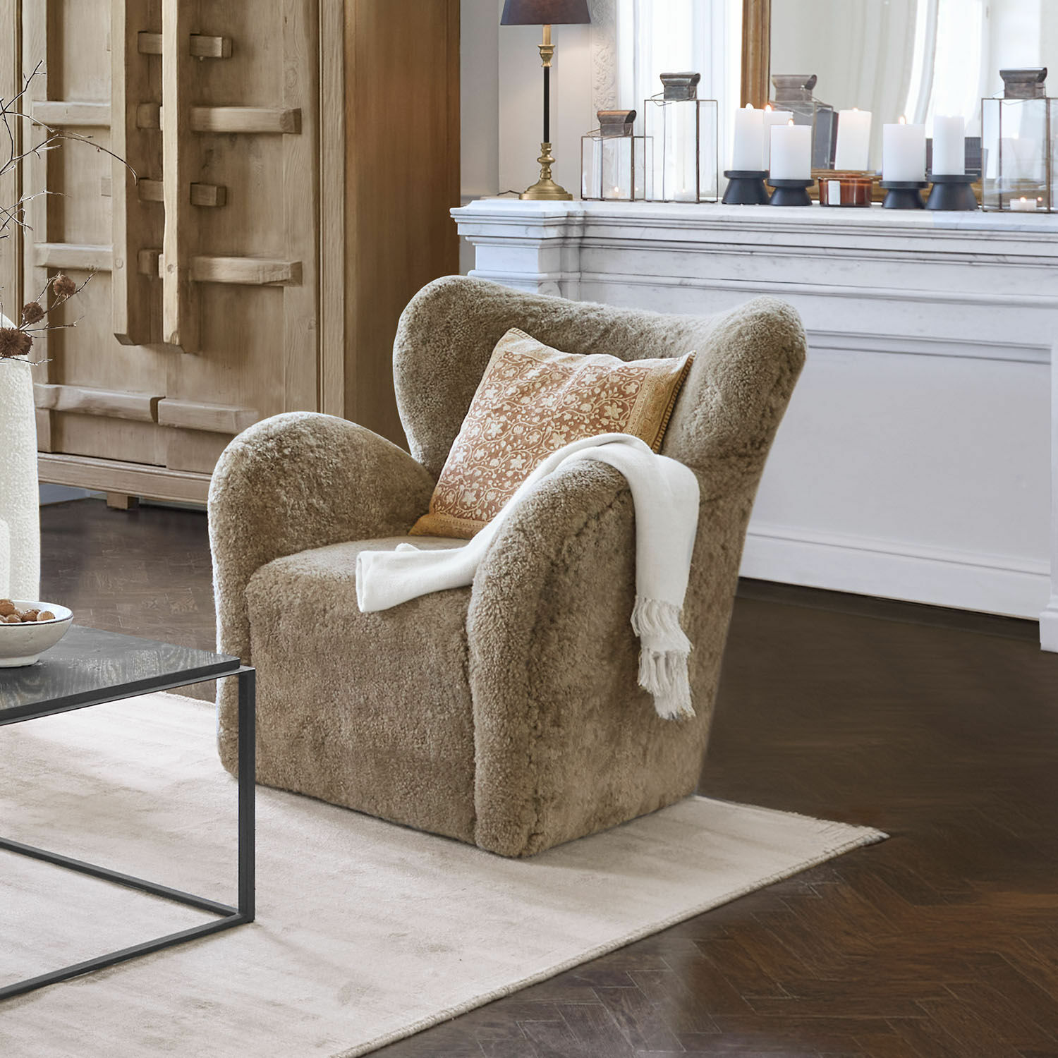 Sessel Ambrécourt Beiger Sessel aus weichem Material mit Kissen und weißer Decke im eleganten Wohnzimmer