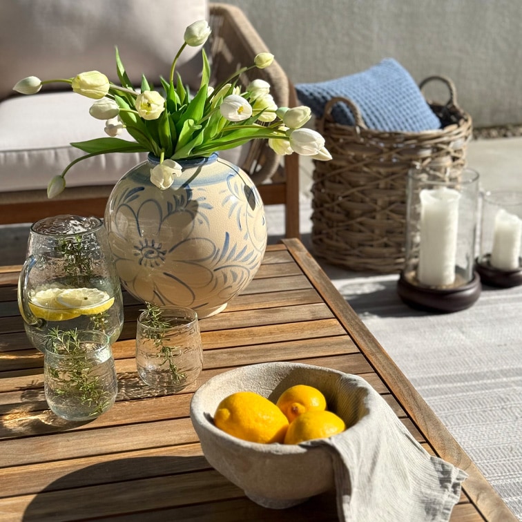 Dekorativer Keramikvase mit Blumenmuster und weißen Tulpen auf Holztisch auf der Terrasse