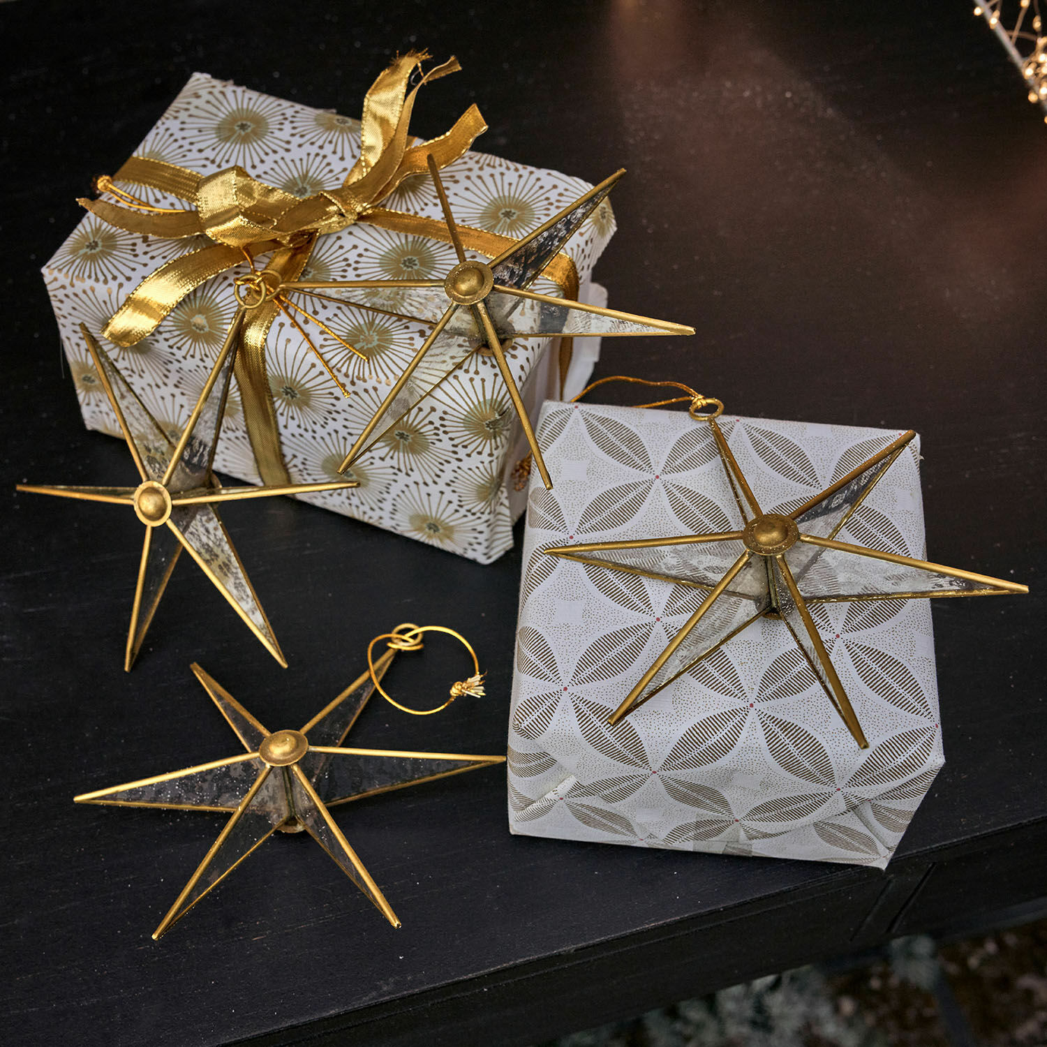 Anhänger 4er Set Zaydan Goldene Metall-Sterne als Dekoration auf Geschenken mit weißem Geschenkpapier und goldener Schleife