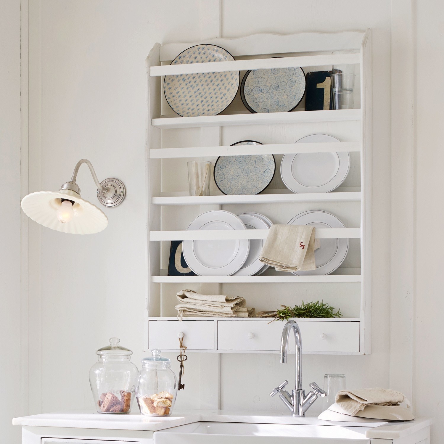 Weißes Holzregal mit Tellern und Gläsern im rustikalen Stil, Küchenwanddeko mit Schubladen
