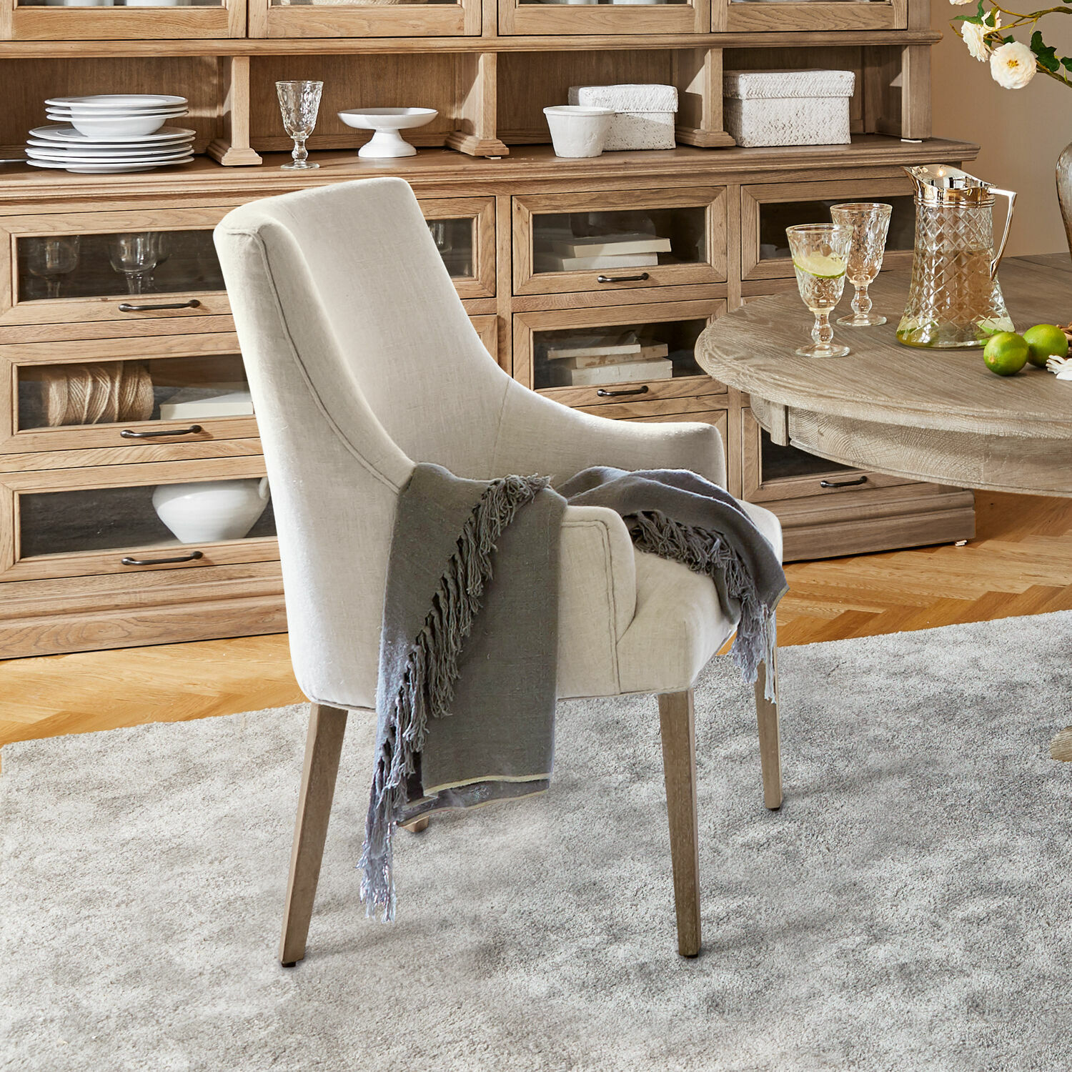 Stuhl Hyeres Beiger Polsterstuhl mit Holzbeinen und grauem Plaid in gemütlichem Wohnzimmer mit Holzkommode