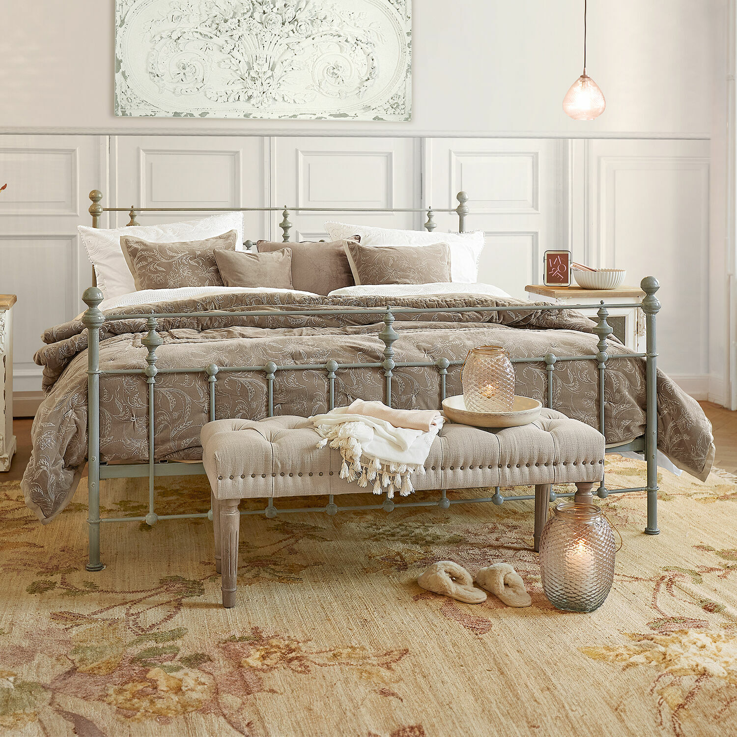 Bett Beauvierre Schlafzimmer mit grauem Metallbett, beiger Bettwäsche mit Blumenmuster und gepolsterter Bank am Fußende