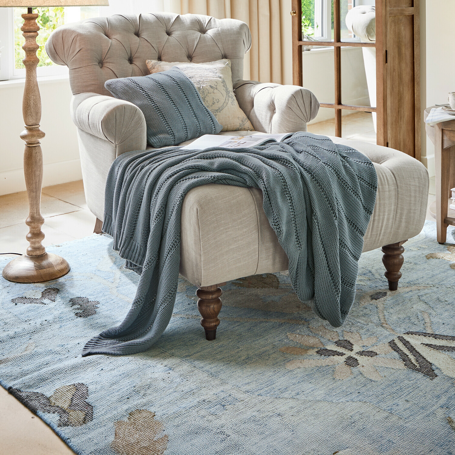 Plaid Lémeré Beiger Polsterfotel mit gesteppter Rückenlehne und blauem Strickplaid im Wohnzimmer