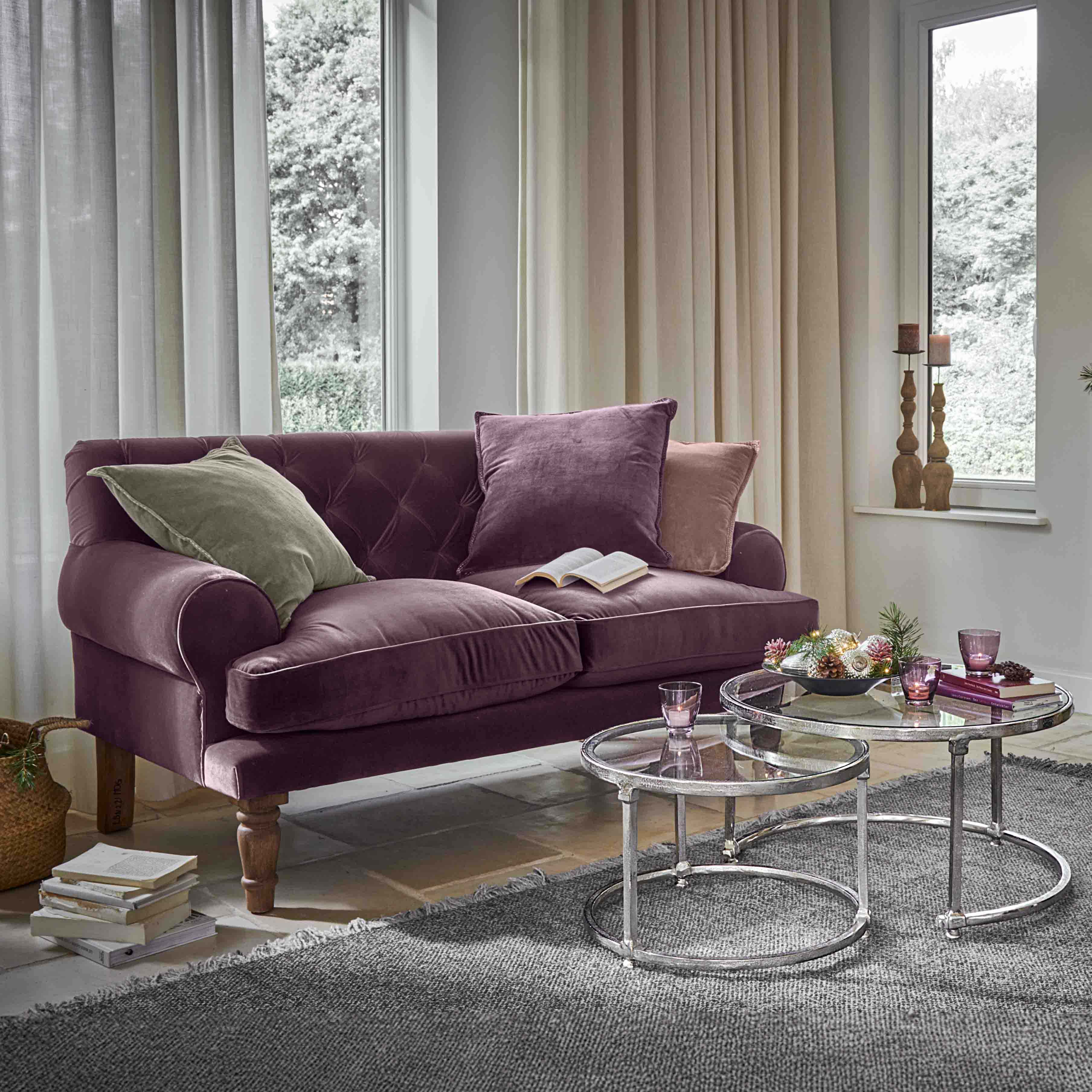 Violettes Samtsofa mit Kissen und runden Glastischen in hellem Wohnzimmer