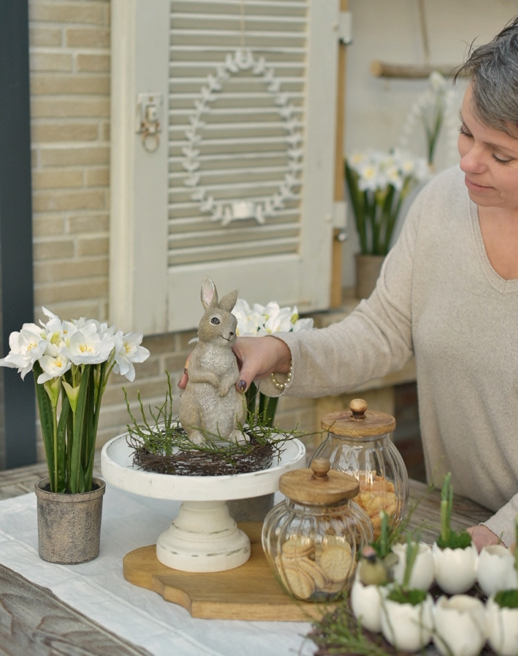 Natürliche Osterdekoration mit Hasenfigur, weißen Blumen und Glasbehältern für Kekse