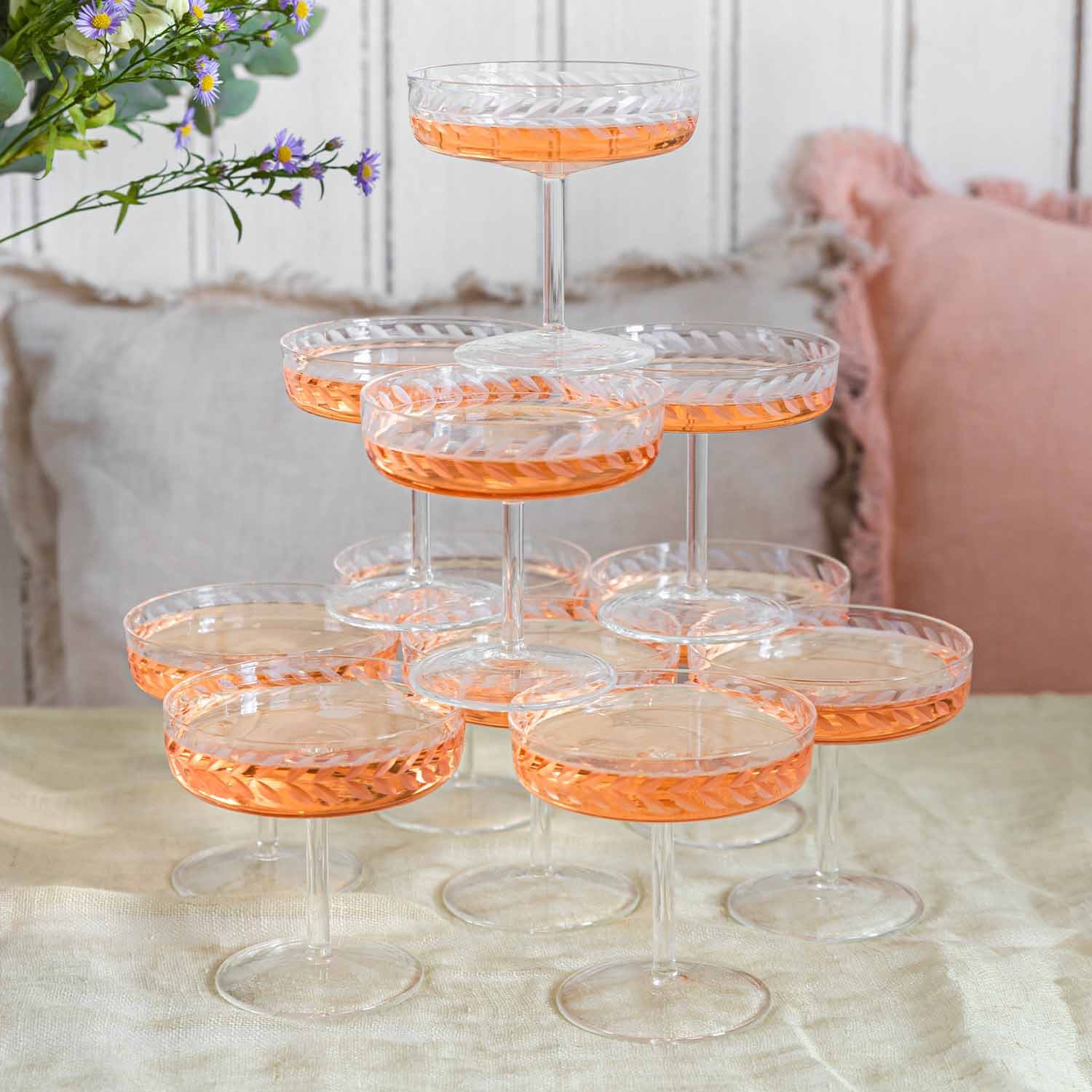 Set aus Kristall-Sektgläsern mit feinem Muster und roséfarbenem Getränk auf Tisch