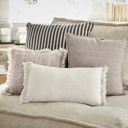 Vier dekorative Kissen in neutralen Farben auf beigem Sofa, Wohntextilien für das Wohnzimmer