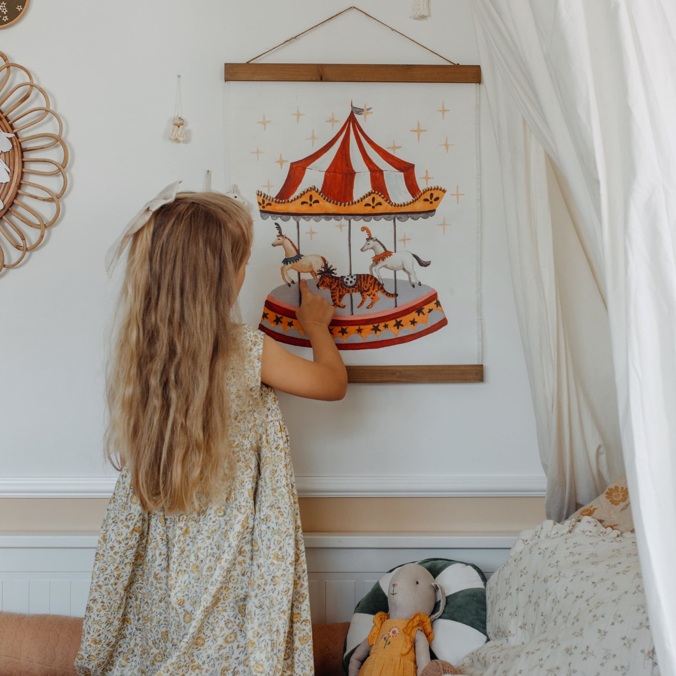 Kind berührt rot-weißes Karussell-Wandbild in gemütlichem Kinderzimmer